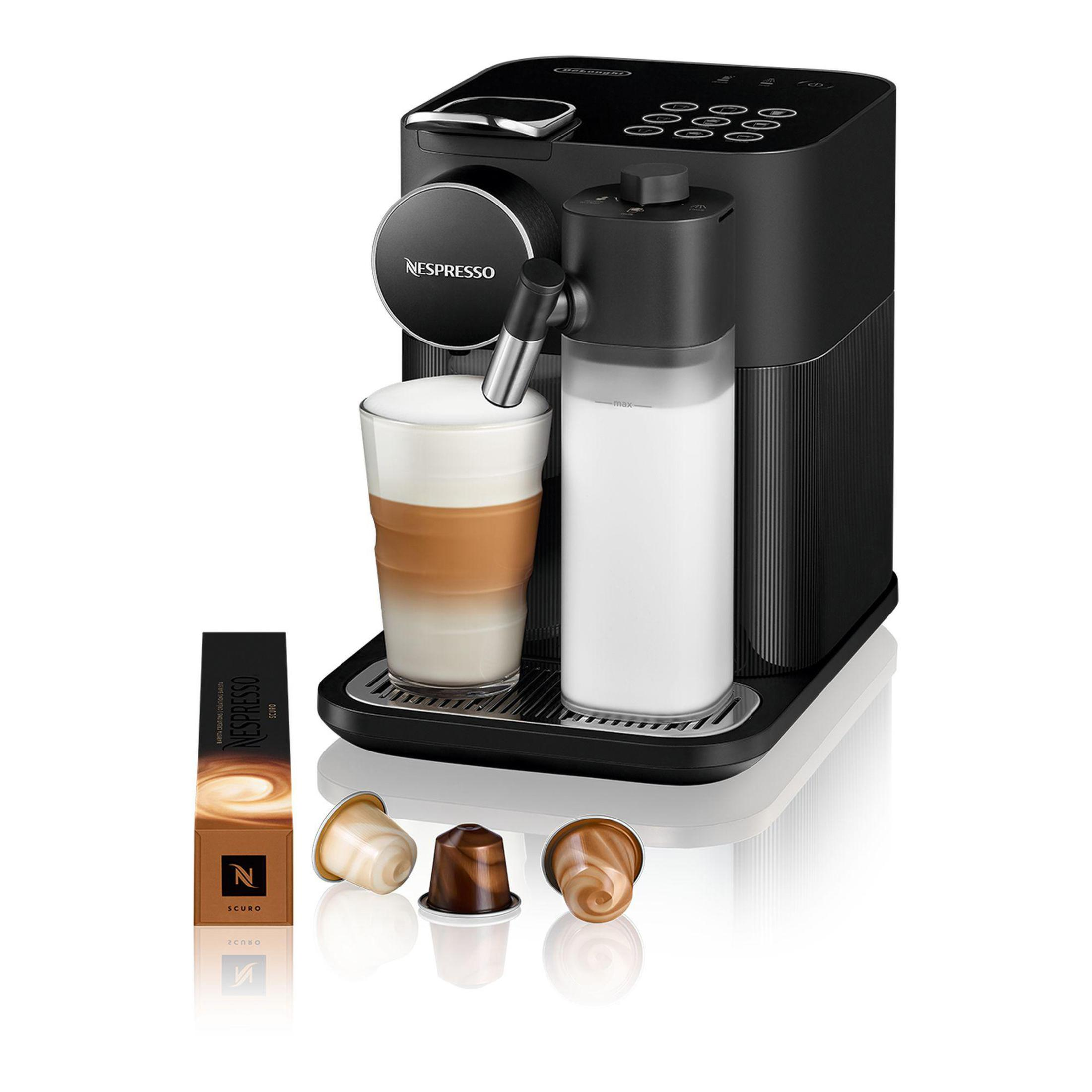 Cafetera Nespresso negra con espumador de leche y cápsulas de café. Fondo blanco.