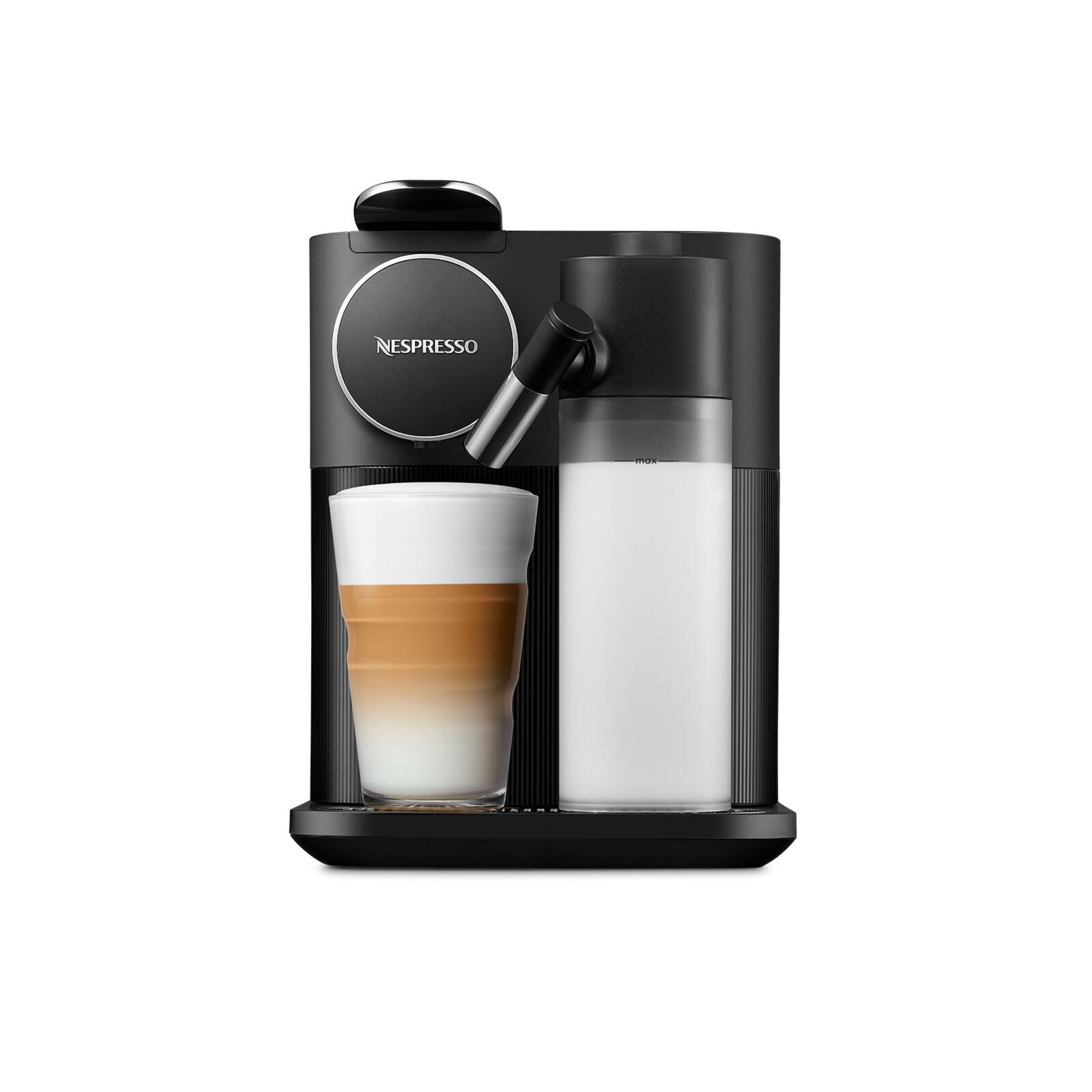 Cafetera Nespresso negra con taza de café y recipiente de leche, fondo blanco.