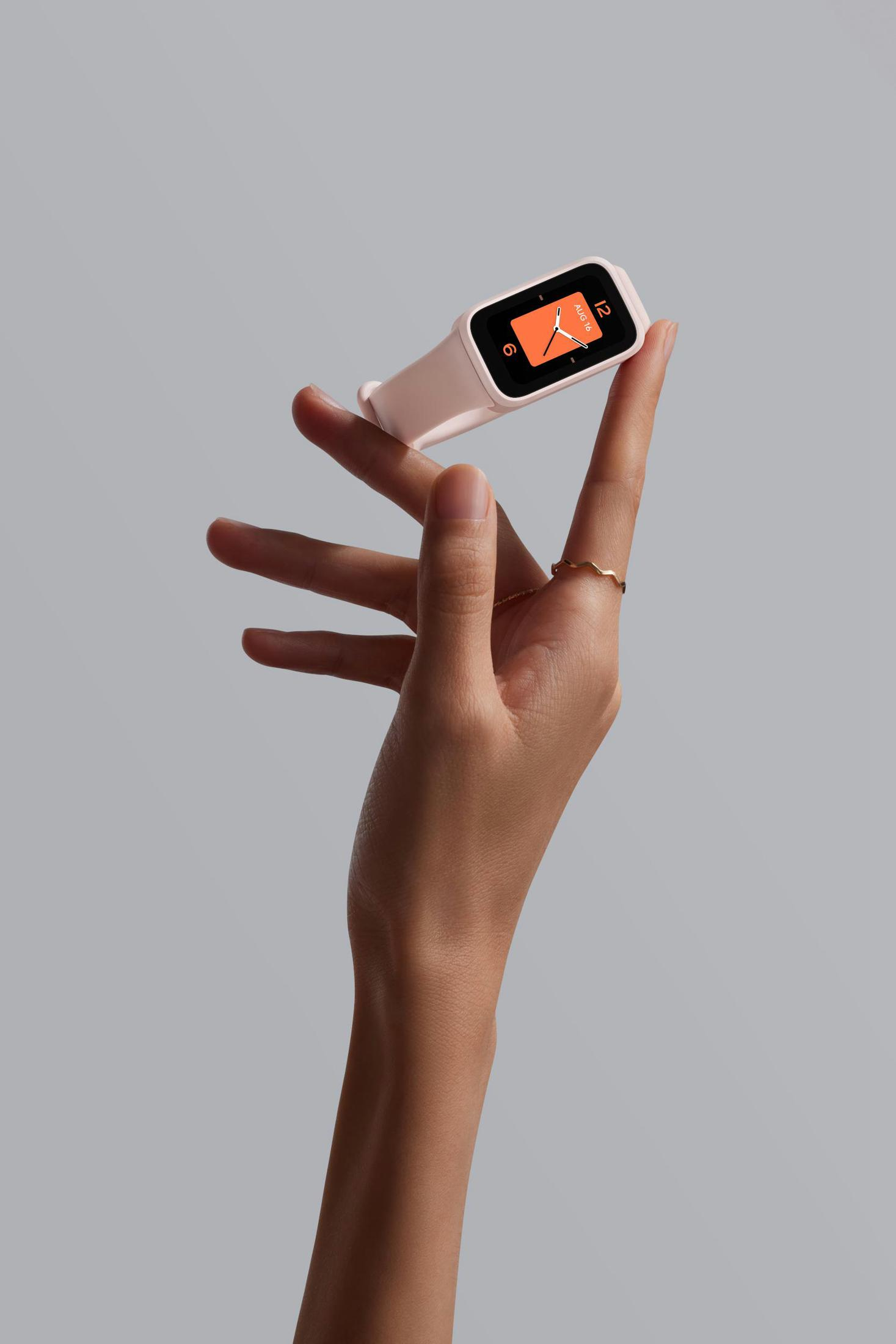 Dłoń trzymająca różowy smartwatch z pomarańczowym ekranem pokazującym godzinę.