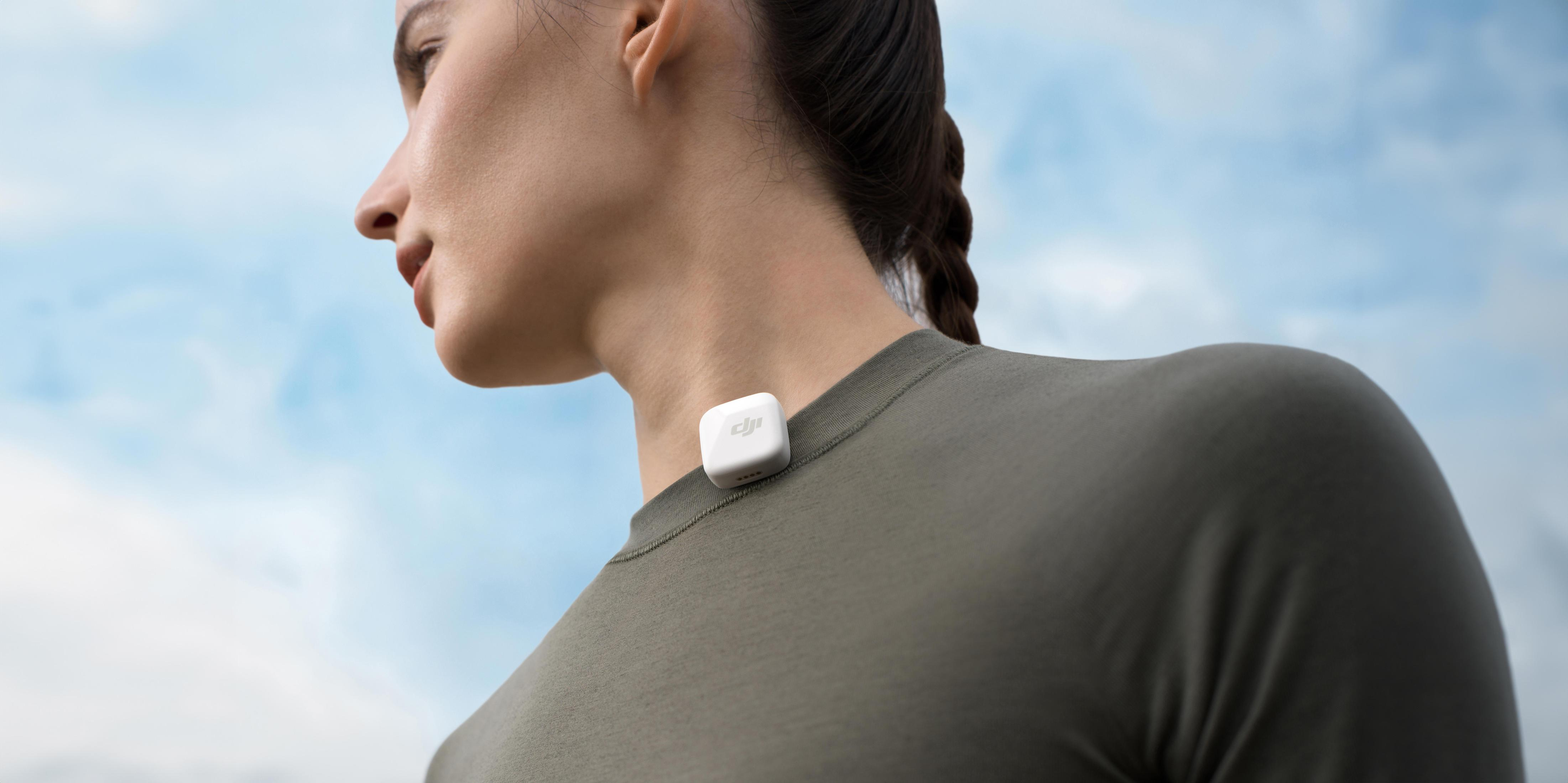 Kobieta w szarej koszuli. Małe białe urządzenie przymocowane do szyi.