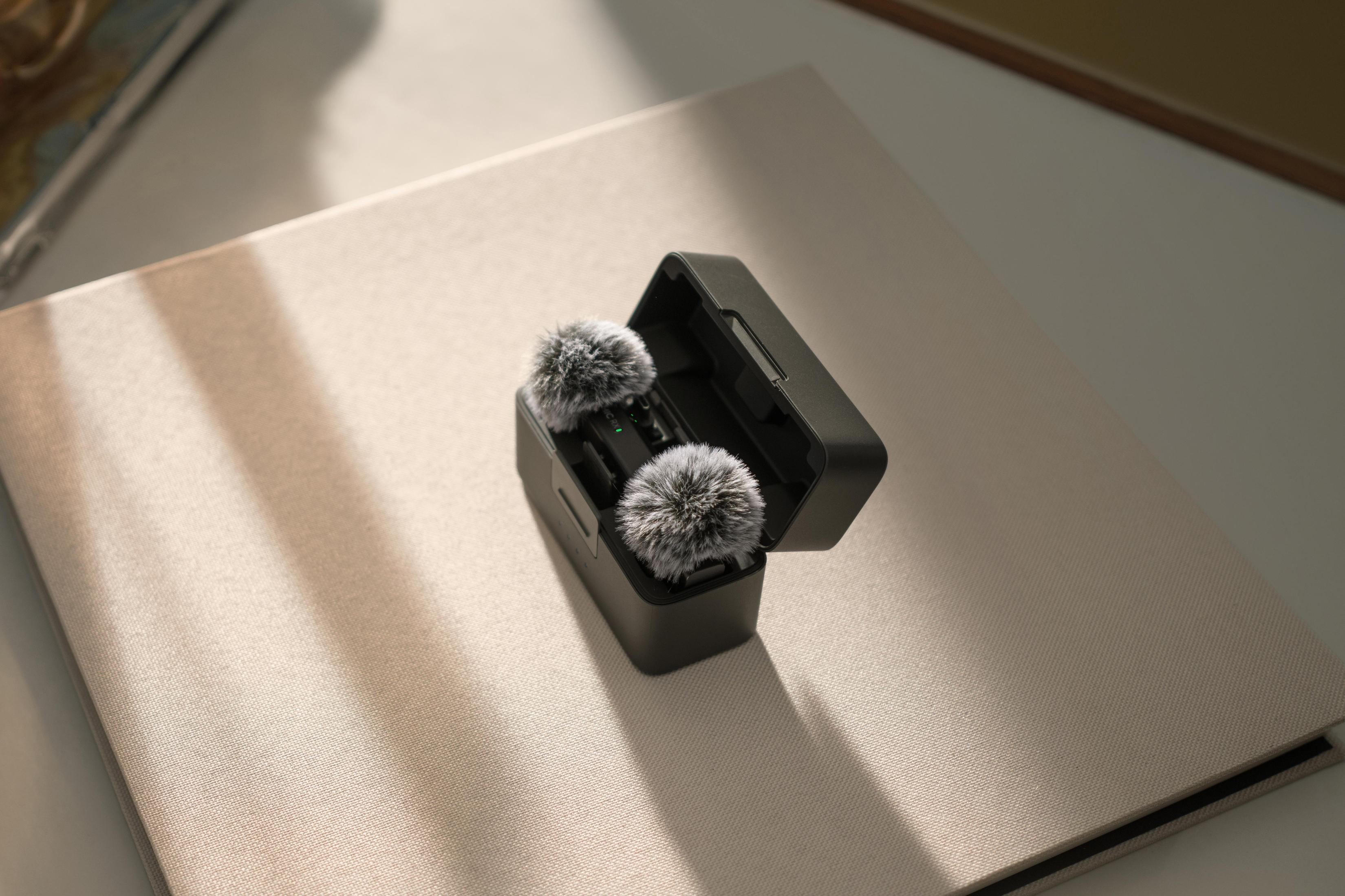 Czarna obudowa z dwoma mikrofonami w środku. Mikrofony mają puszyste, szare osłony przeciwwiatrowe.