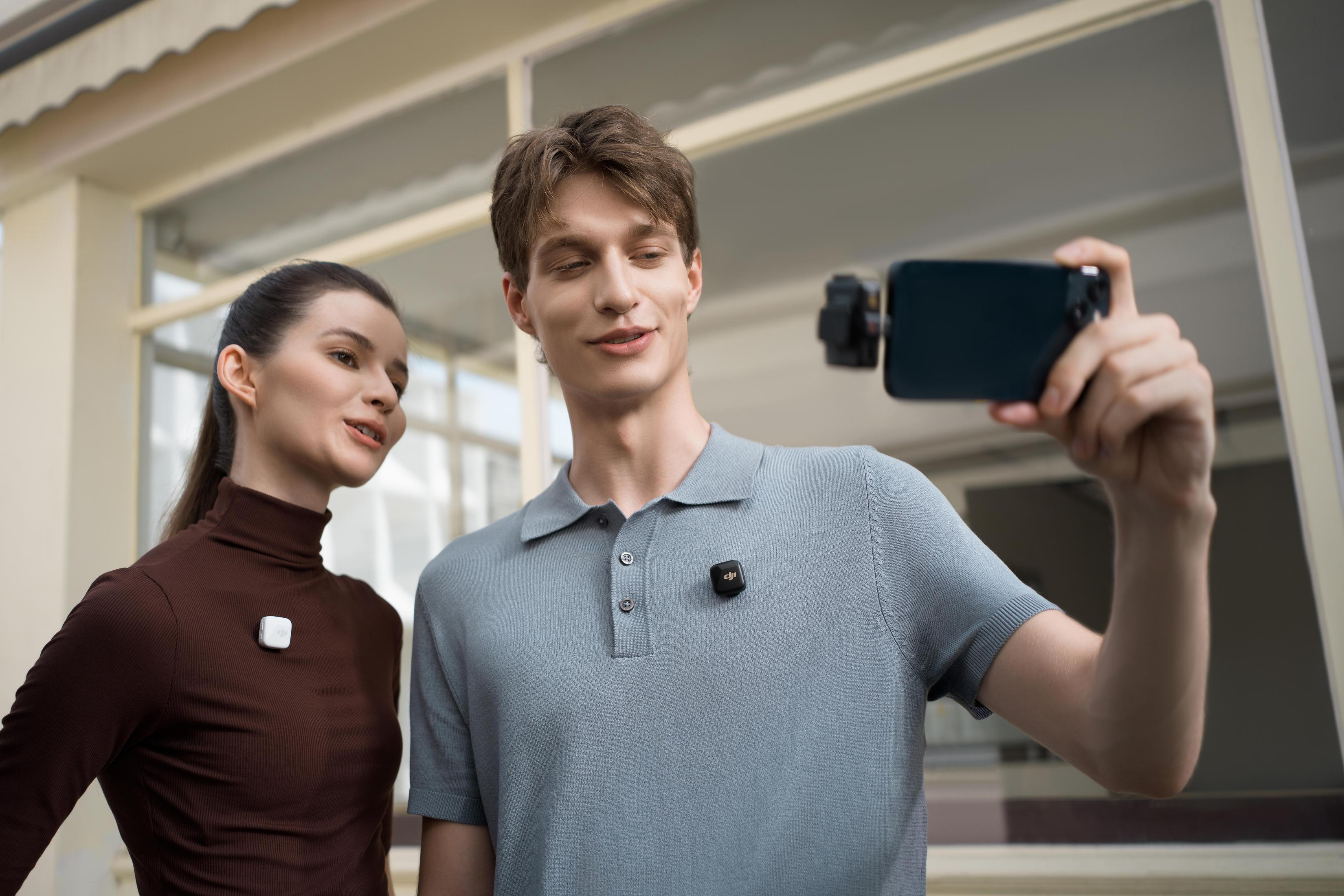 Dwie osoby z mikrofonami robiące selfie smartfonem.