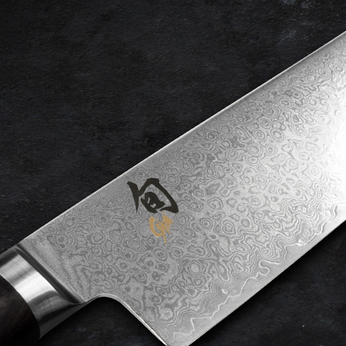 Zbliżenie ostrza noża kuchennego z wzorzystą metalową powierzchnią.