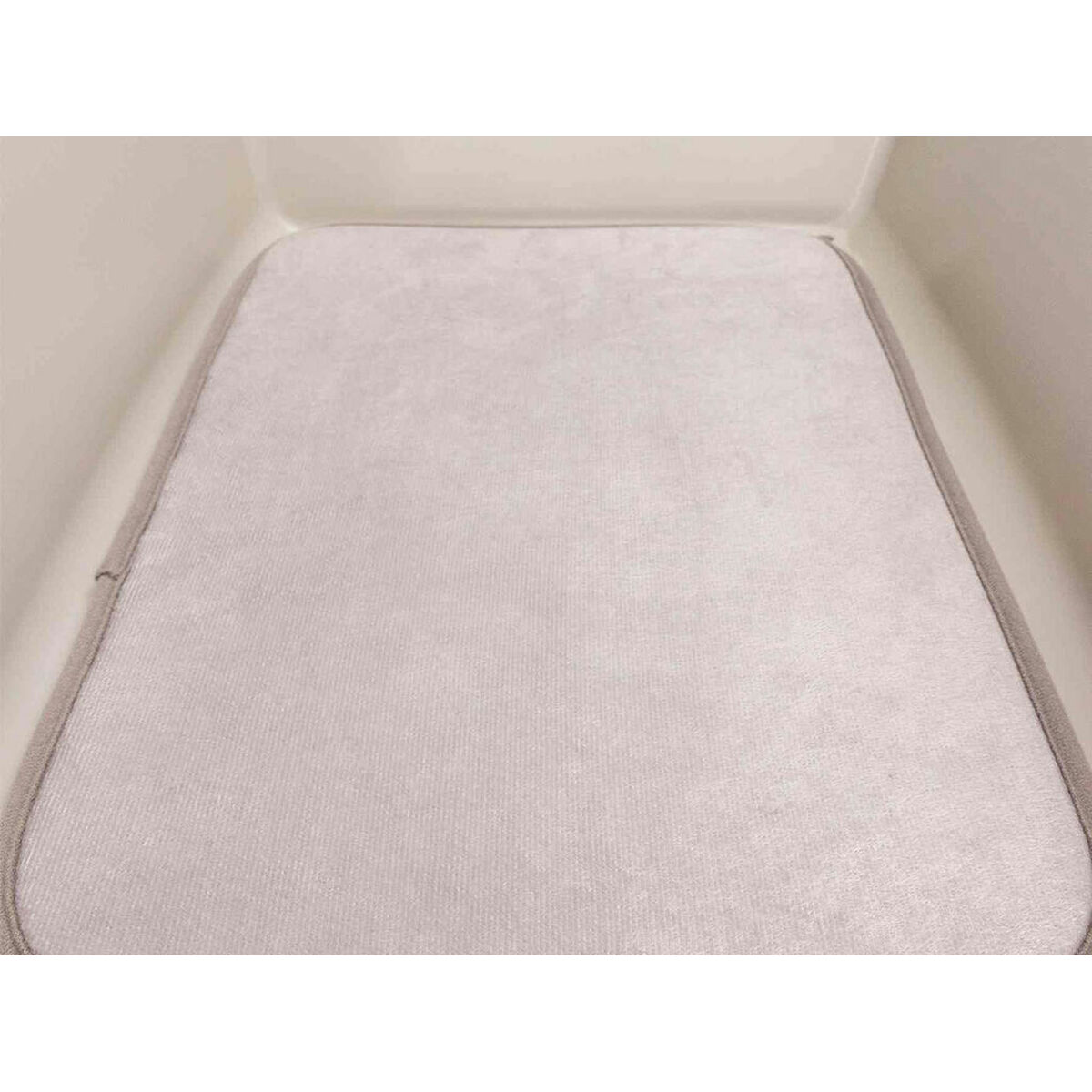Un tappetino rettangolare beige chiaro all'interno di un contenitore beige, forse per un animale domestico.