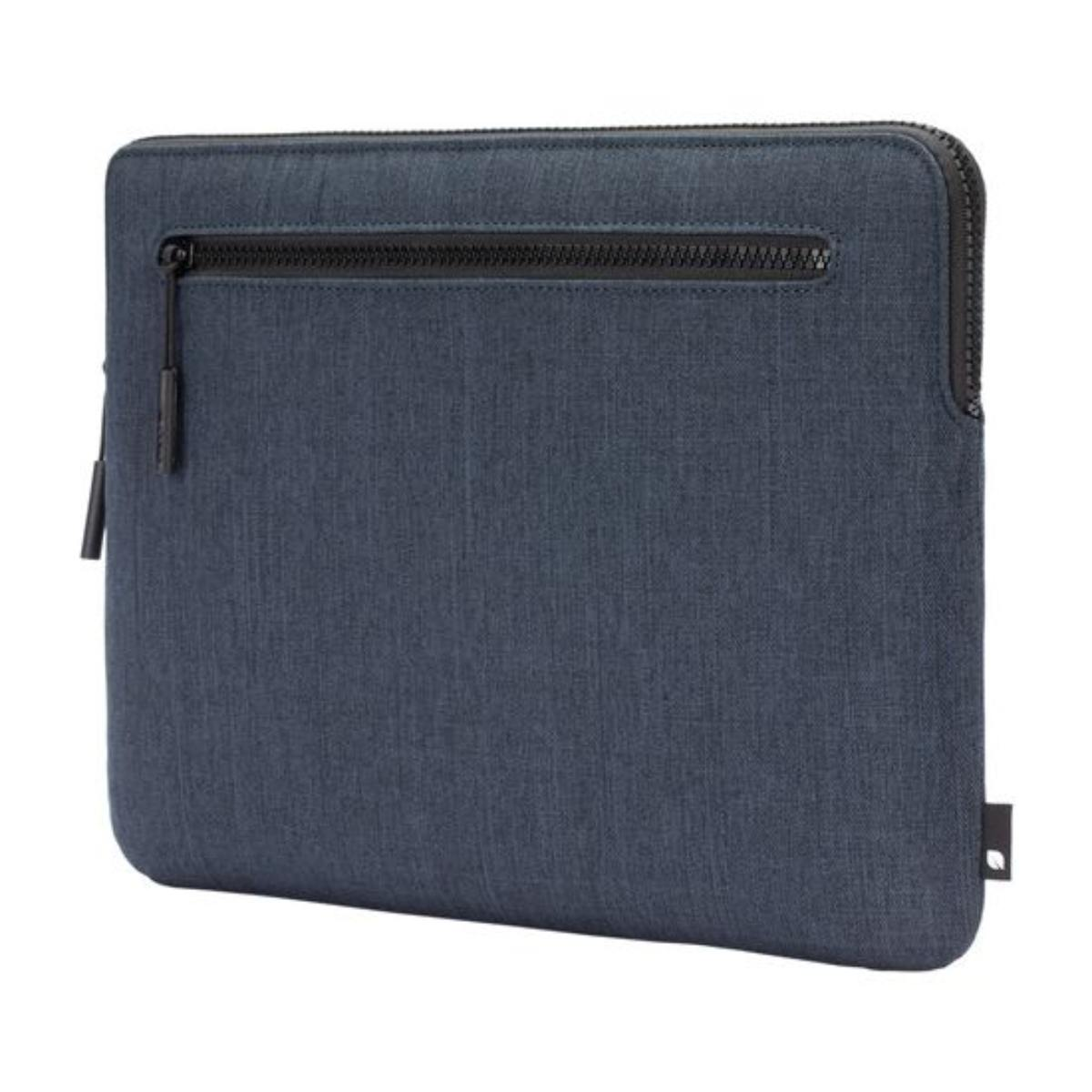 Custodia per laptop blu scuro. Caratterizzata da una cerniera nera e una piccola linguetta. Il tessuto ha un aspetto strutturato.