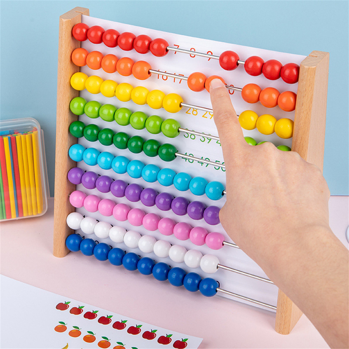 Holzabakus mit farbigen Perlen. Eine Hand zeigt auf die Perlen. Weißer Hintergrund.