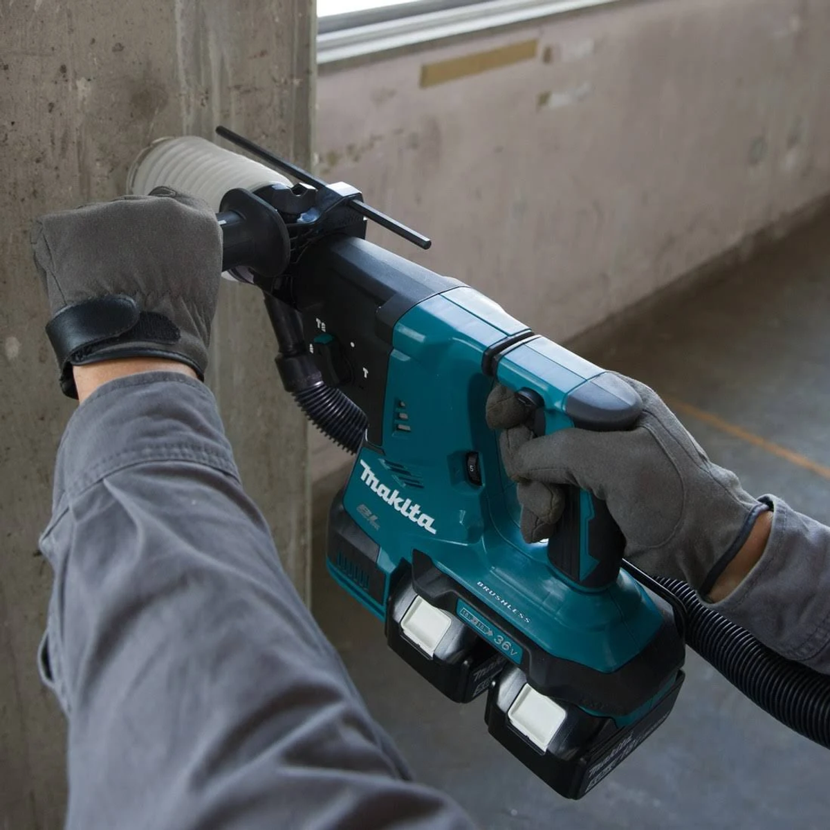 Persona usando una herramienta eléctrica Makita verde azulado para taladrar en una pared de hormigón.