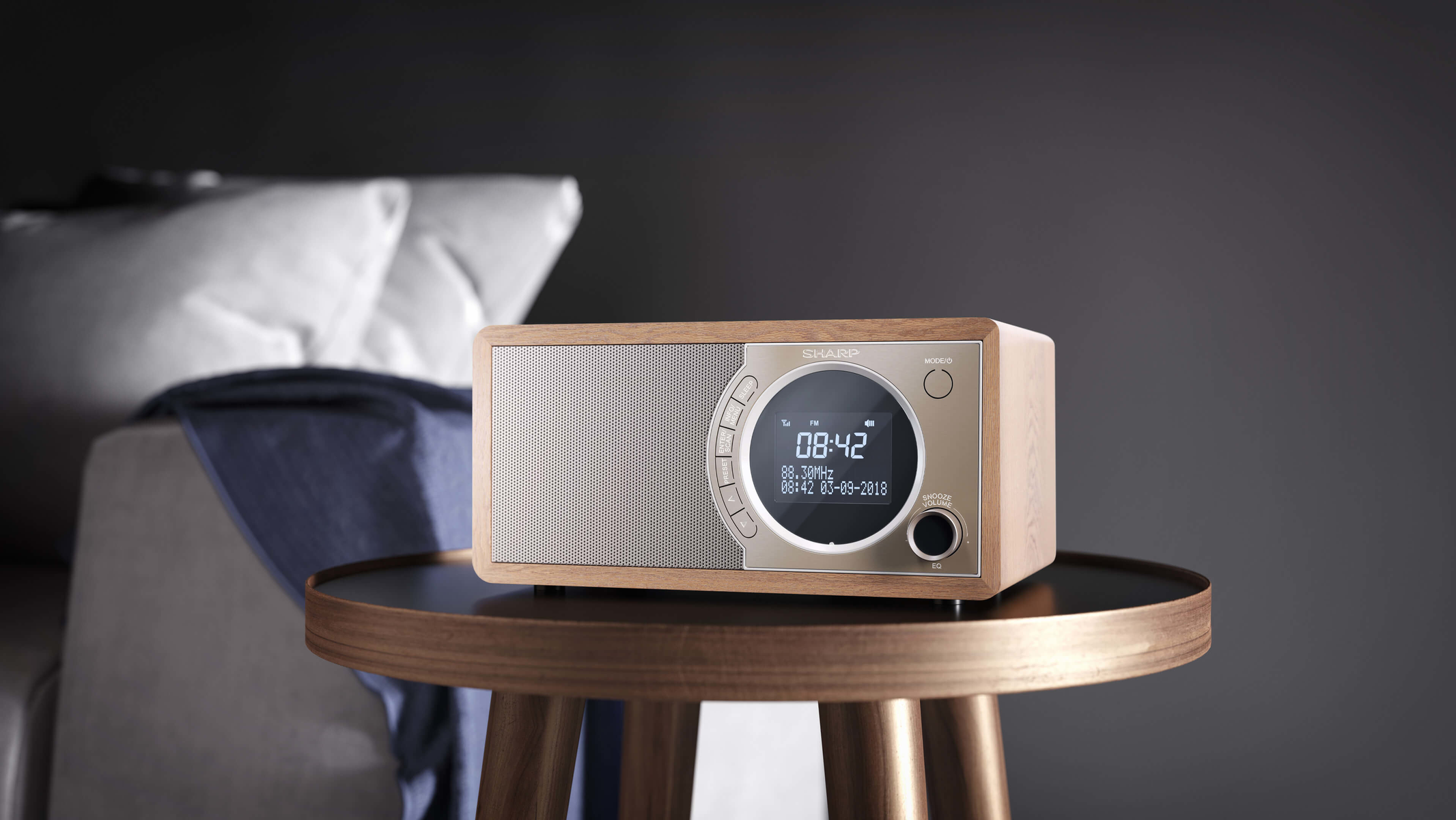Drewniane radio Sharp z wyświetlaczem cyfrowym, na drewnianym stoliku, na ciemnym tle.