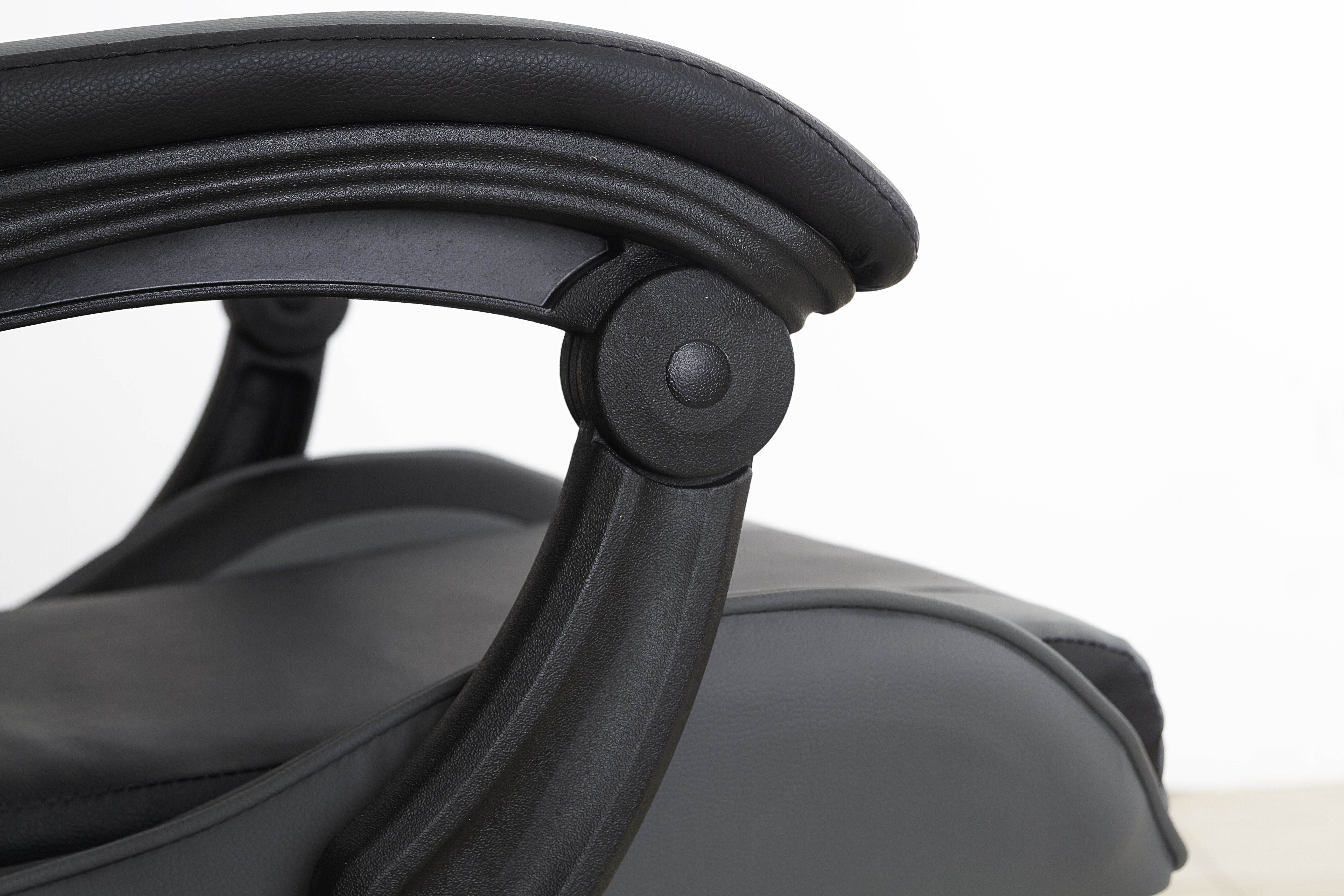 Primer plano del reposabrazos de una silla gaming negra, que muestra el diseño curvo y un punto de conexión.