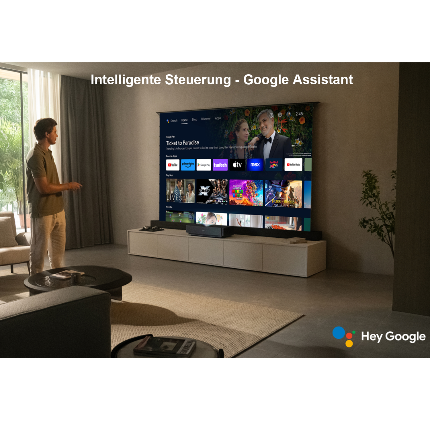 Mann steht vor einem Fernseher mit Google Assistant-Oberfläche.