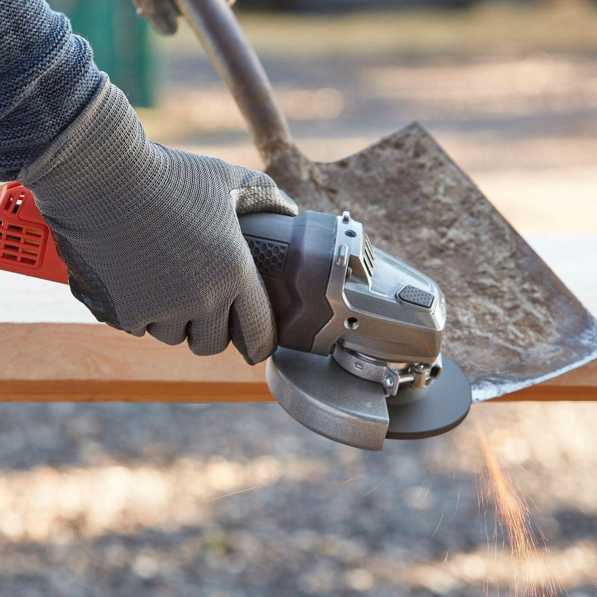 Persona usando amoladora angular en madera. Chispas volando. Guante gris, madera y metal son visibles.