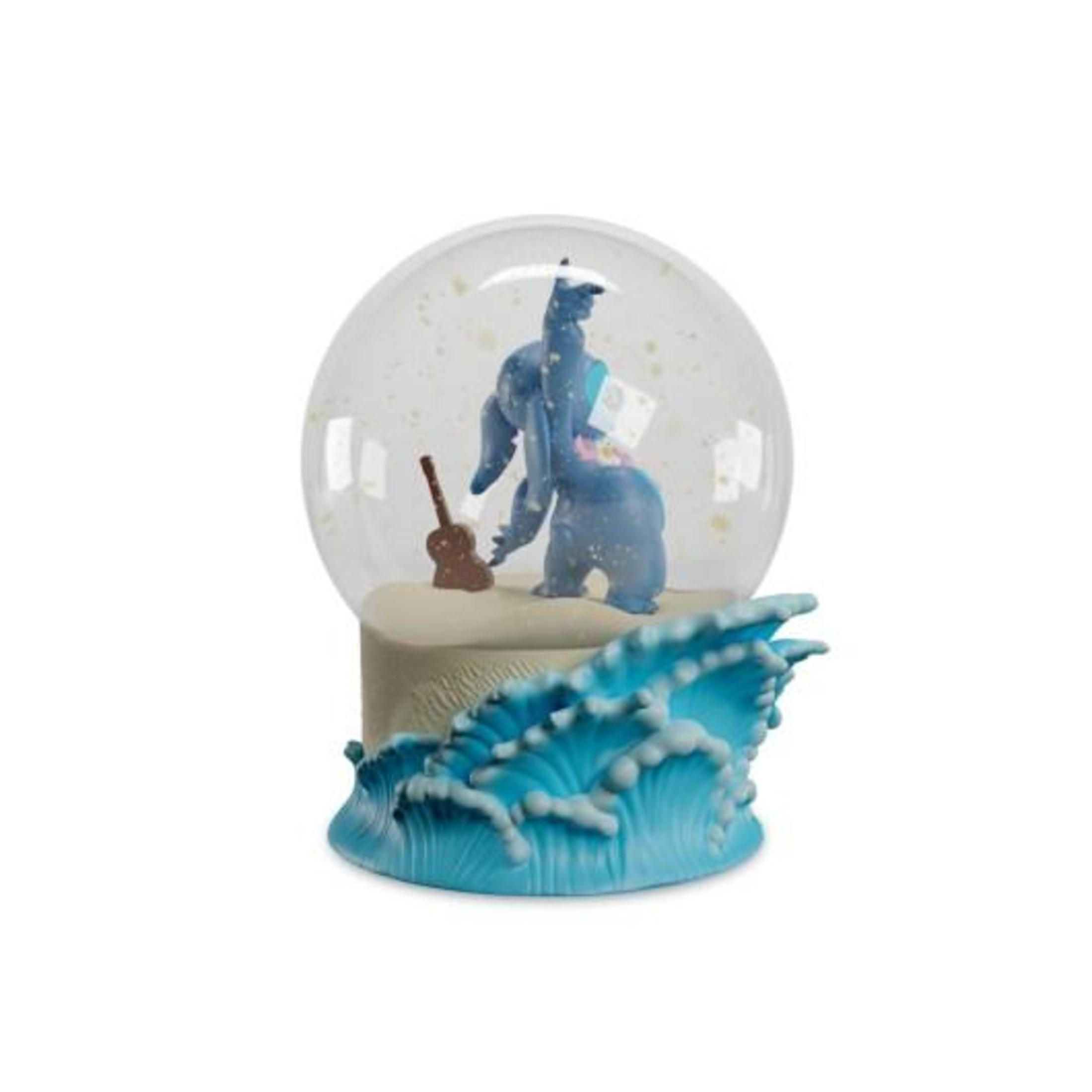 Schneekugel mit einer blauen Figur, die Gitarre spielt. Eine braune Gitarre und eine Wellenbasis.