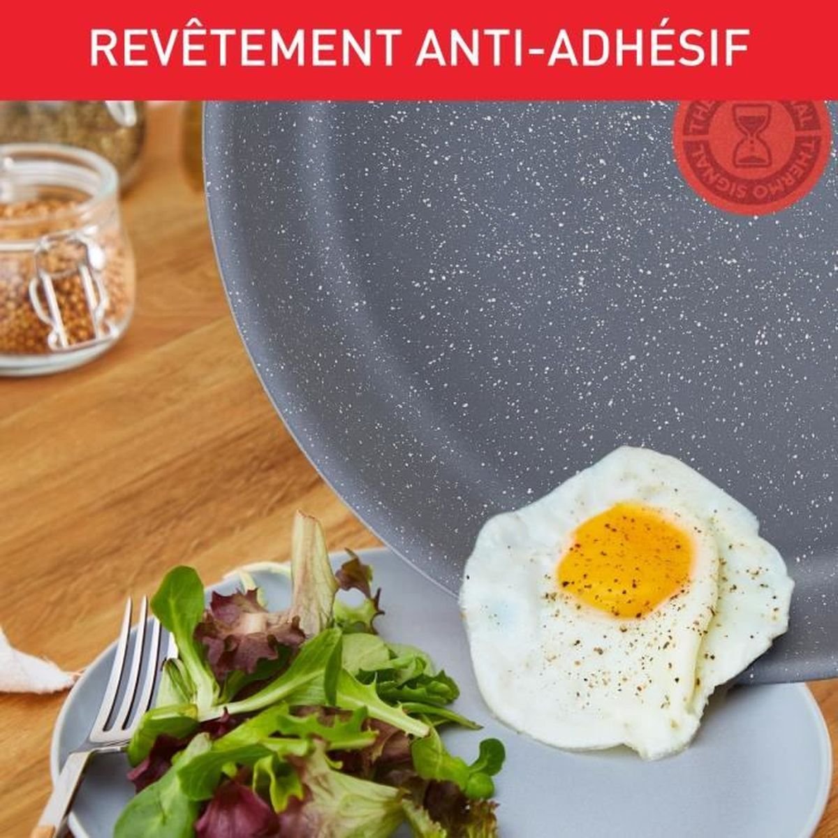 Eine Bratpfanne mit Spiegelei und Salat. Der Hintergrund ist eine Kücheneinrichtung.