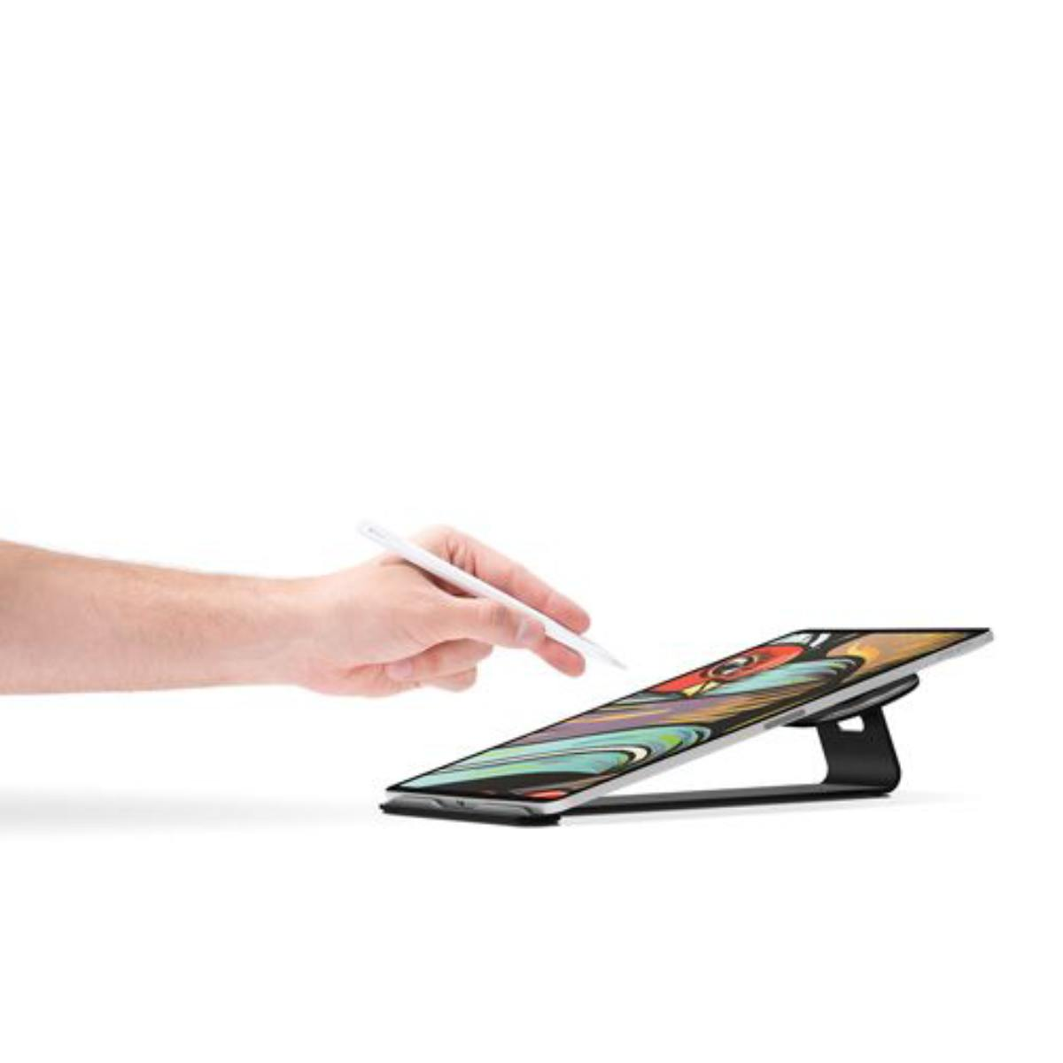 La main d'une personne tenant un stylet sur une tablette, qui est soutenue par un support noir. Fond blanc.
