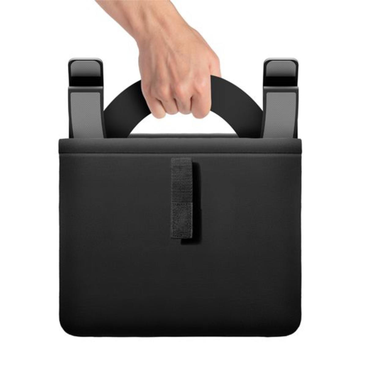 A black bag with a handle held by a hand. The bag has two gray supports on top and a velcro strap.