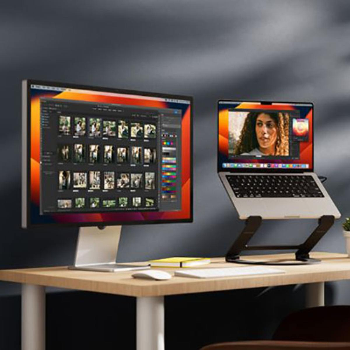 A laptop on a stand next to a monitor showing a photo editing interface.