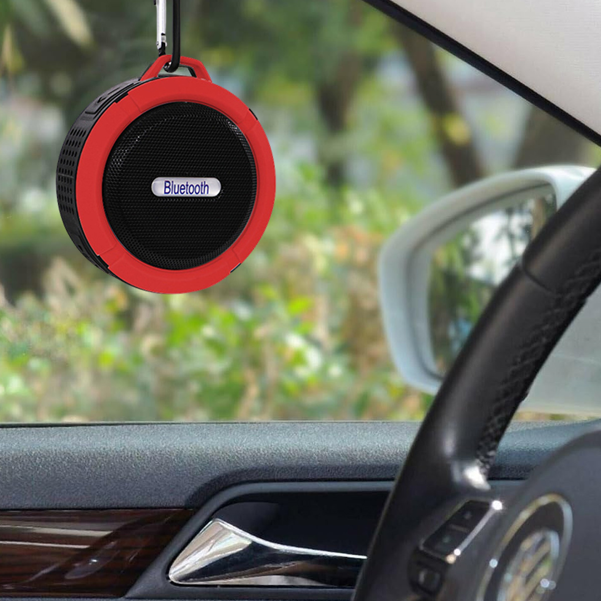 Roter und schwarzer Bluetooth-Lautsprecher, der im Auto hängt. Der Innenraum ist sichtbar.