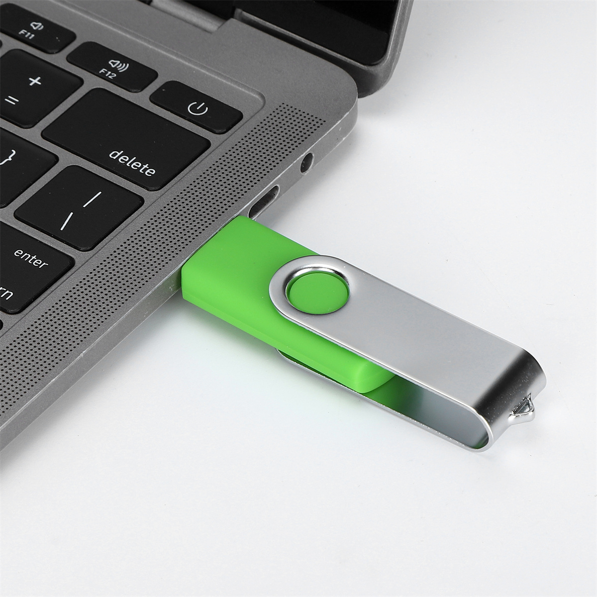 Ein grüner USB-Stick, der an einen grauen Laptop angeschlossen ist. Silber und grün.