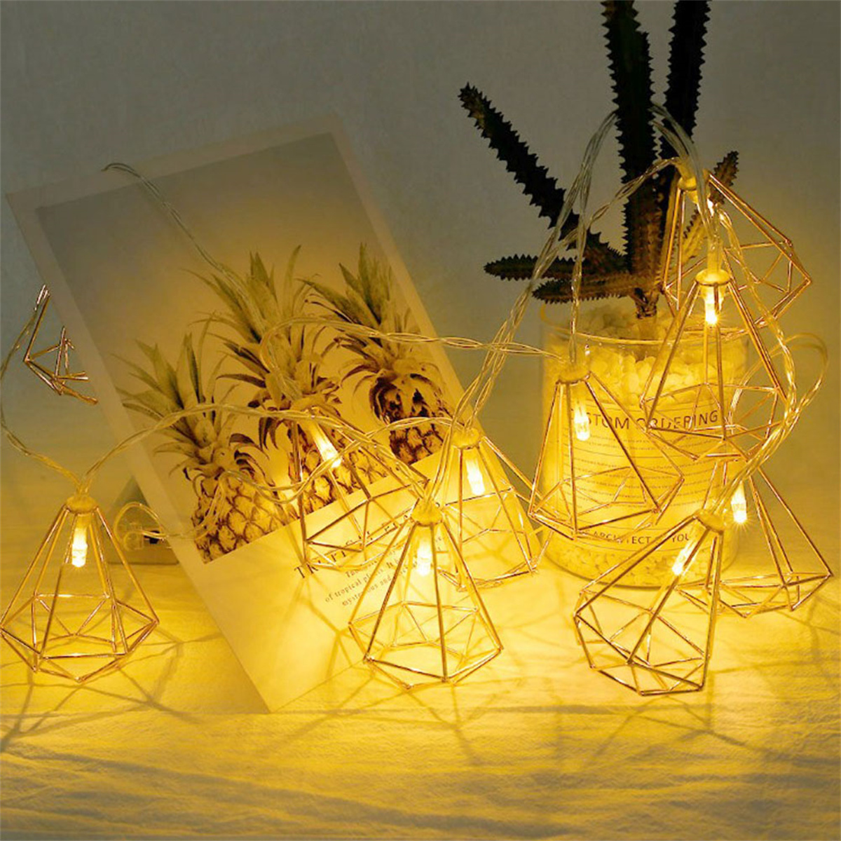 Goldene geometrisch geformte Lichterketten mit weißem Hintergrund und Kunst.