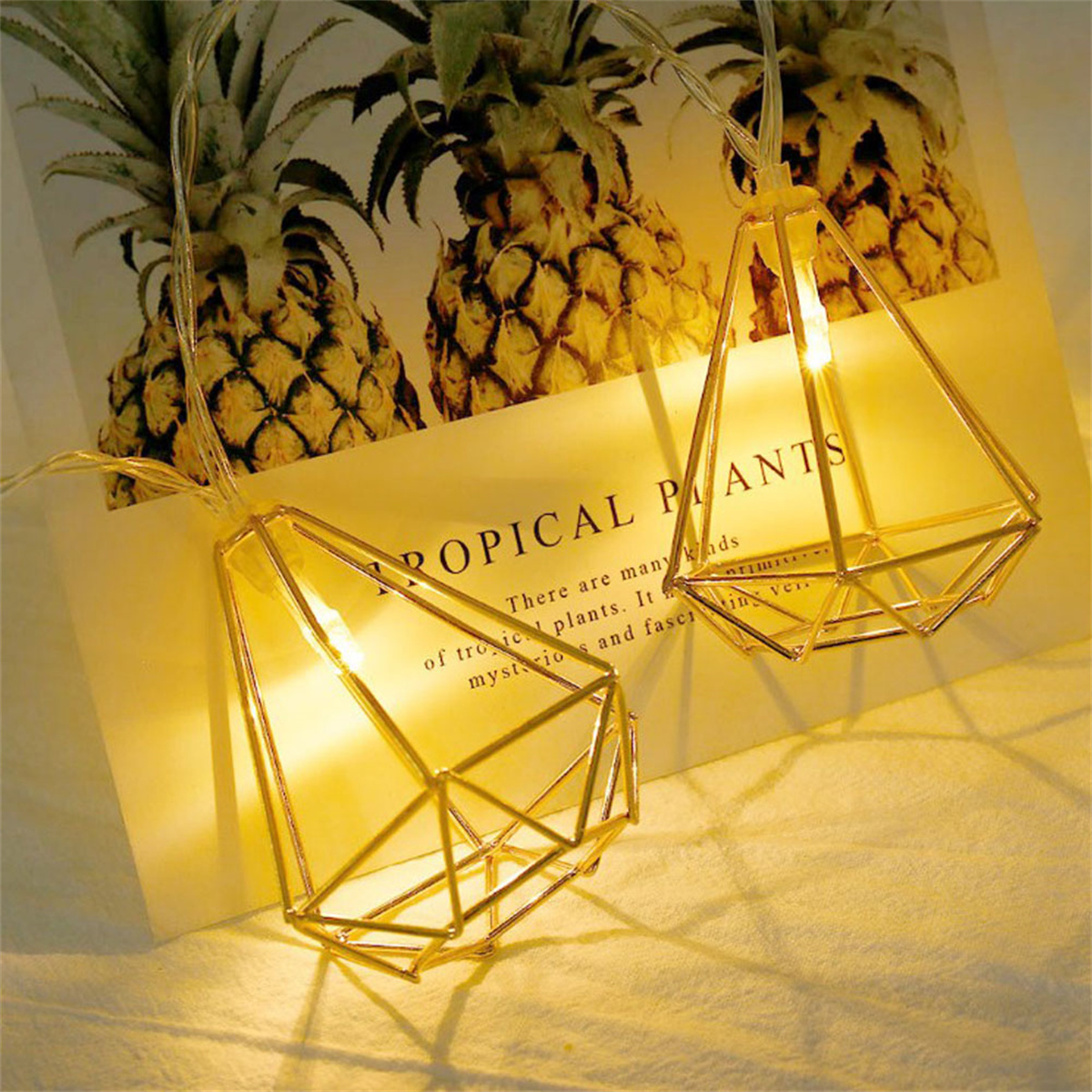 Goldene geometrische Lichter mit Ananas im Hintergrund.