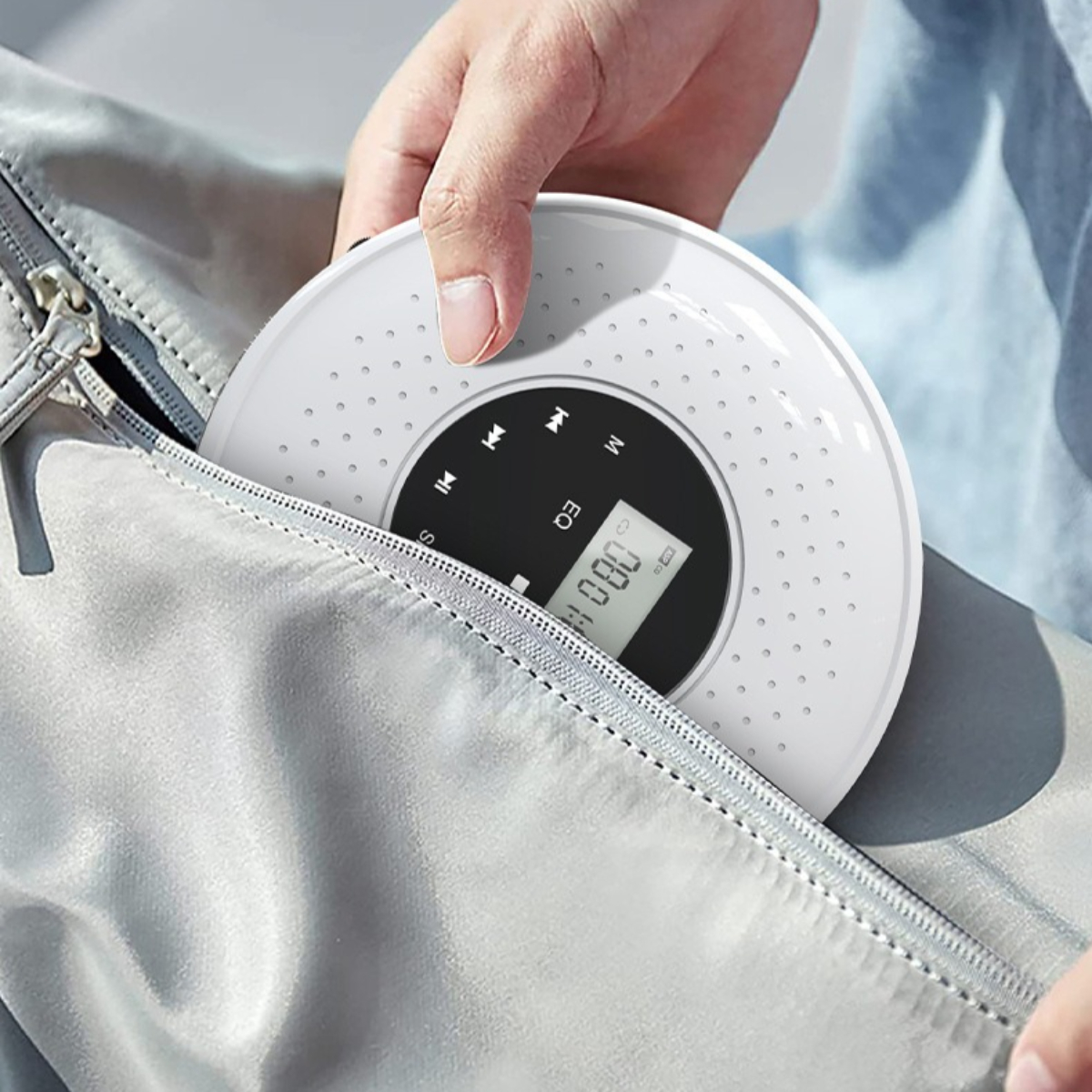 Hand hält einen weißen tragbaren CD-Player, teilweise aus einer grauen Tasche.