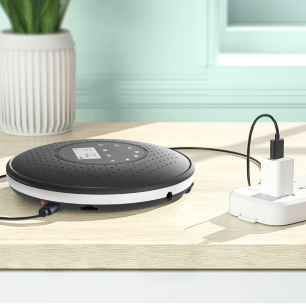 Schwarz-weißer Disc-Player, der mit einem weißen Stecker geladen wird, auf Holzoberfläche.