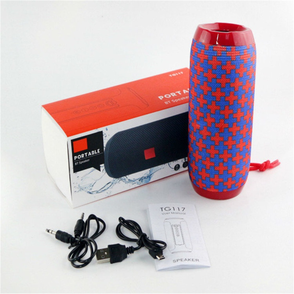 Ein rot-blau gemusterter Lautsprecher, eine Box, Kabel und ein Handbuch auf weißem Untergrund.