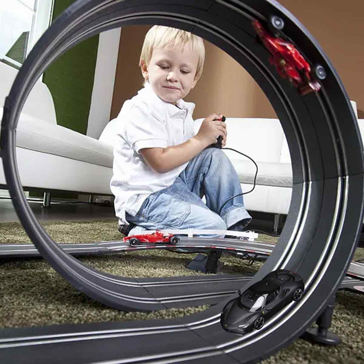 Ein junger Junge spielt mit einem roten und schwarzen Rennwagen-Set auf einer Strecke mit einer Schleife.