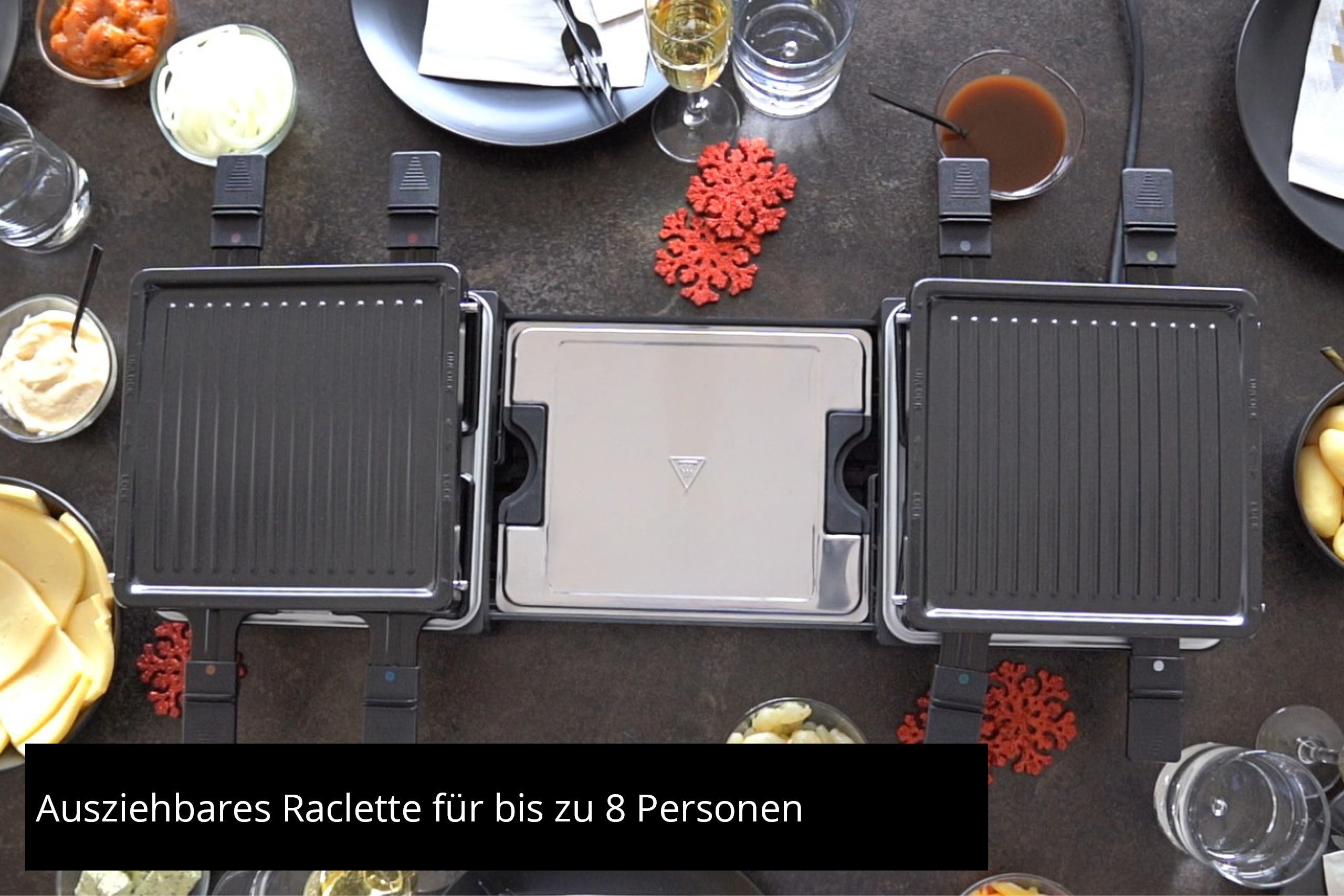 Ein Tisch mit einem Raclette-Grill. Verschiedene Zutaten umgeben ihn, darunter Käse und Zwiebeln.