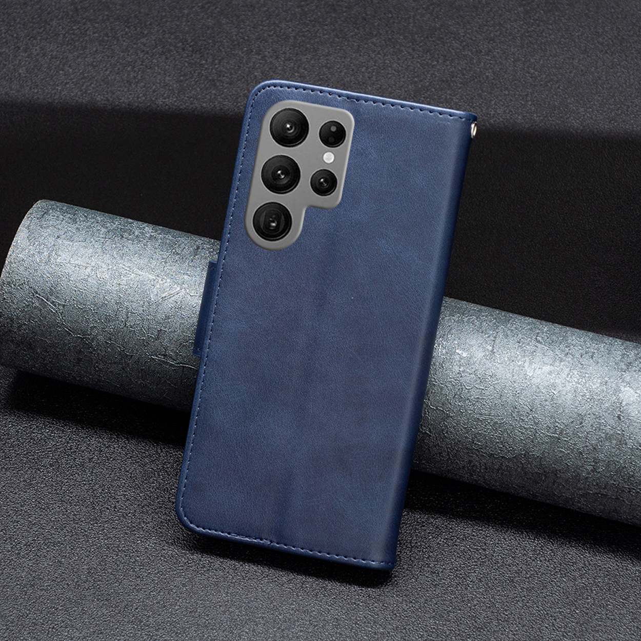 Blauwe telefoonhoes met een telefoon erin. De telefoon heeft meerdere cameralenzen. Donkere achtergrond.
