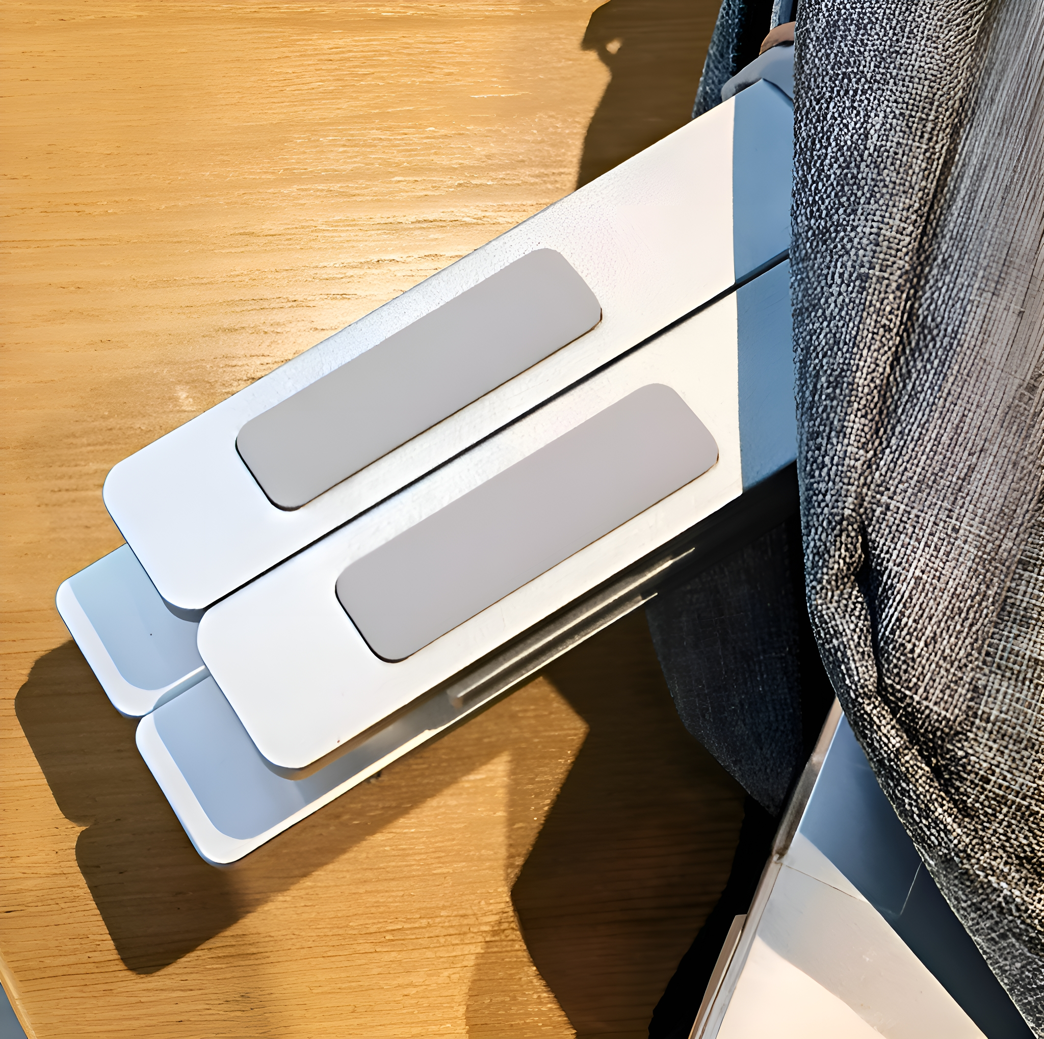 Zwei weiße Laptop-Ständer auf Holzoberfläche. Eine Jeansjacke ist in der Ecke.