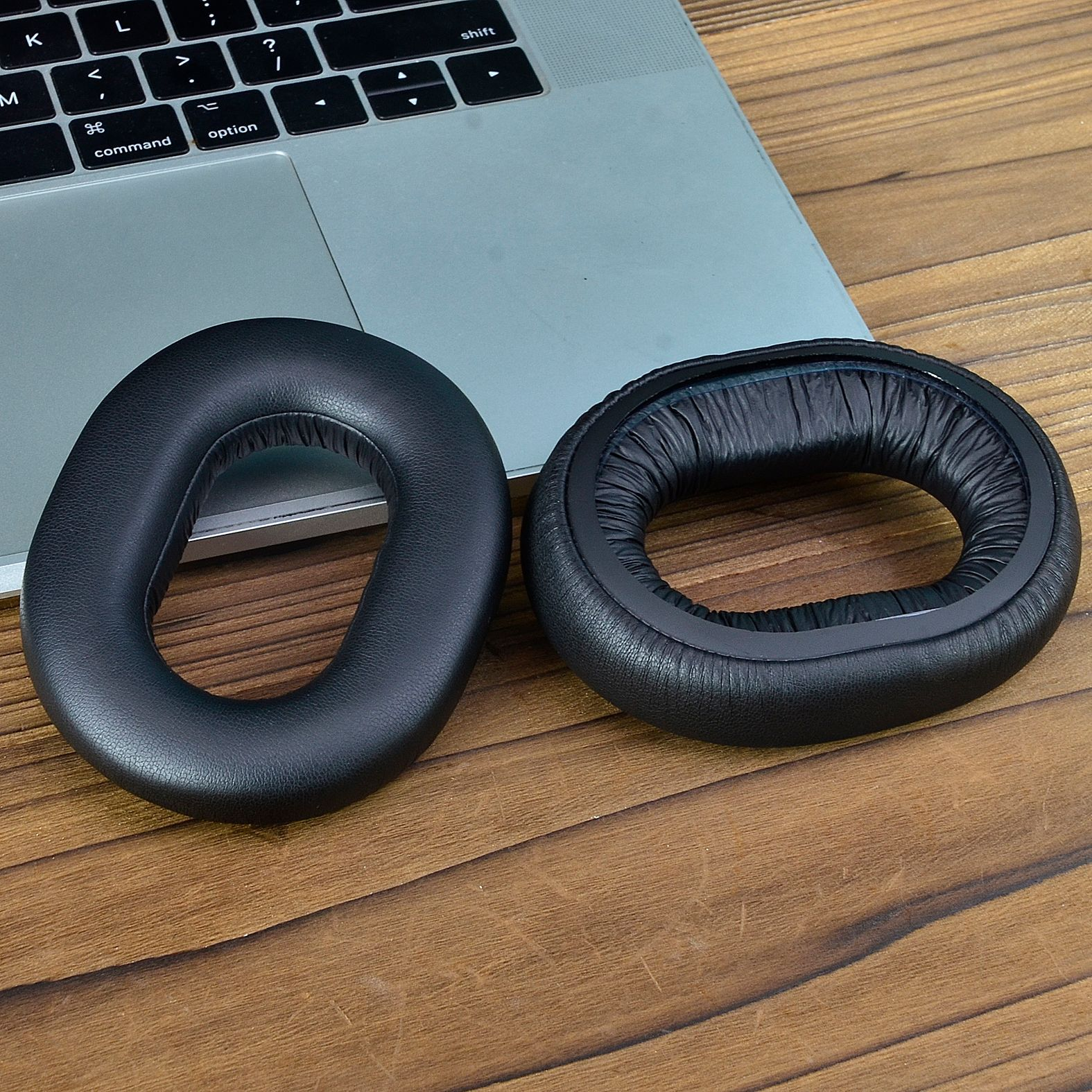 Czarne nauszniki do słuchawek na drewnianej powierzchni.