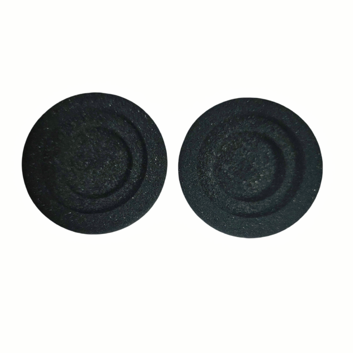 Dwie czarne, okrągłe piankowe nauszniki na białym tle. Mają zakrzywioną konstrukcję.