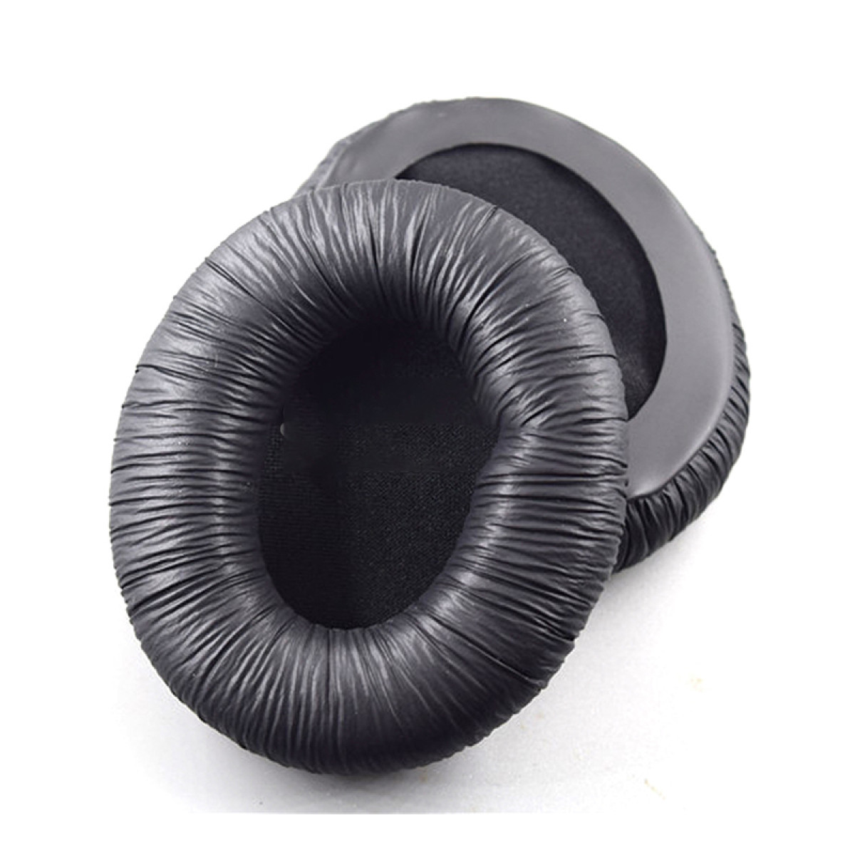 Dwie czarne, okrągłe poduszki nauszne do słuchawek. Wykonane są z prążkowanego, miękkiego materiału. Białe tło.