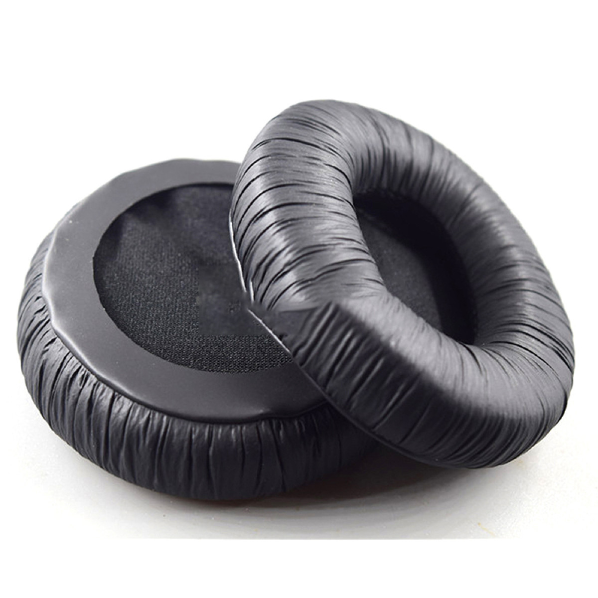 Dwie czarne poduszki na uszy, okrągłe. Są na białym tle.