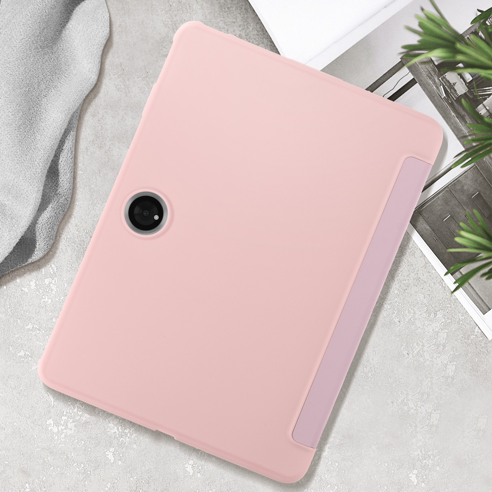 Una tableta rosa con cámara trasera, sobre una superficie texturizada.
