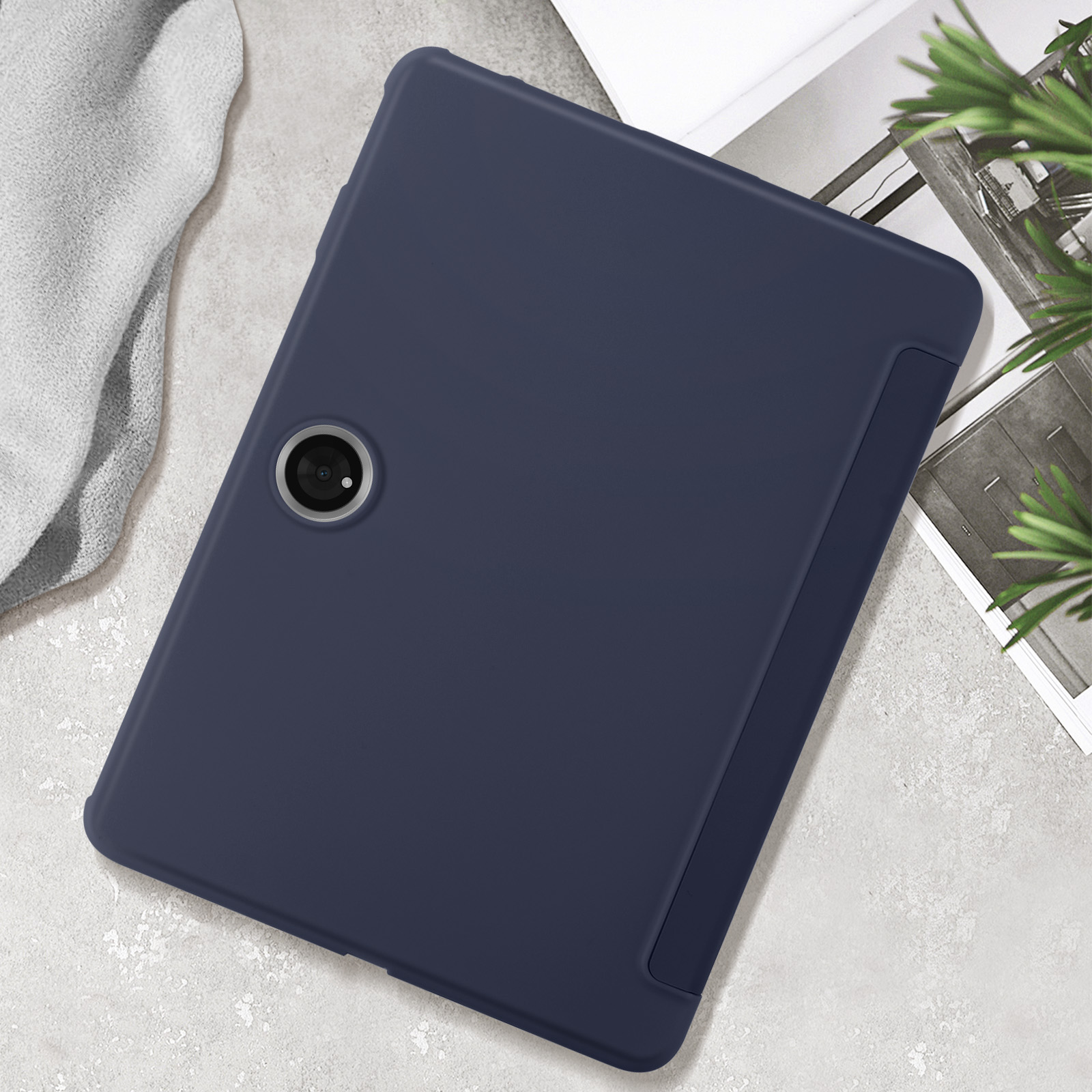 Una custodia per tablet blu navy. La custodia è su una superficie bianca con vegetazione.