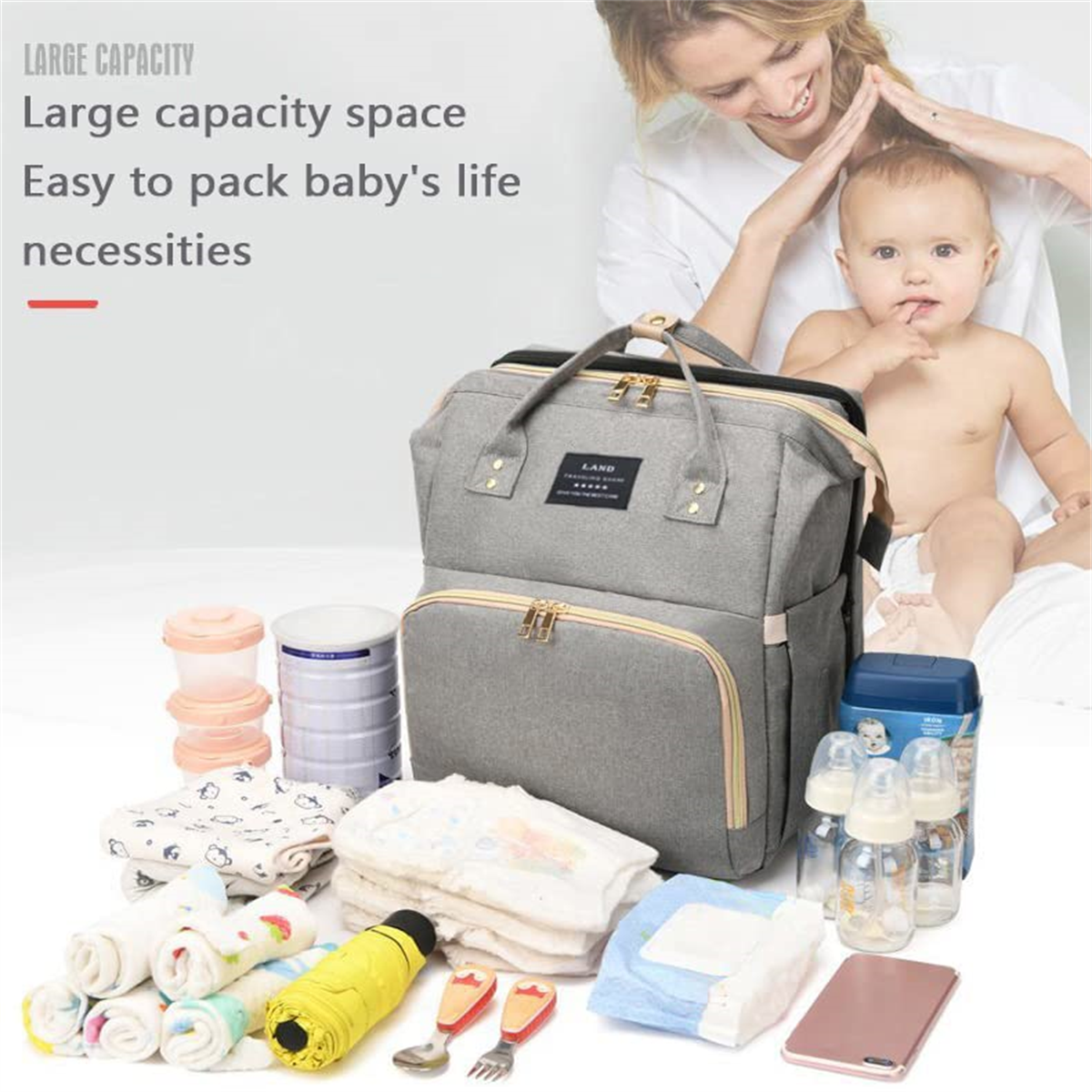 Graue Wickeltasche mit Babyutensilien. Mutter und Baby im Hintergrund.