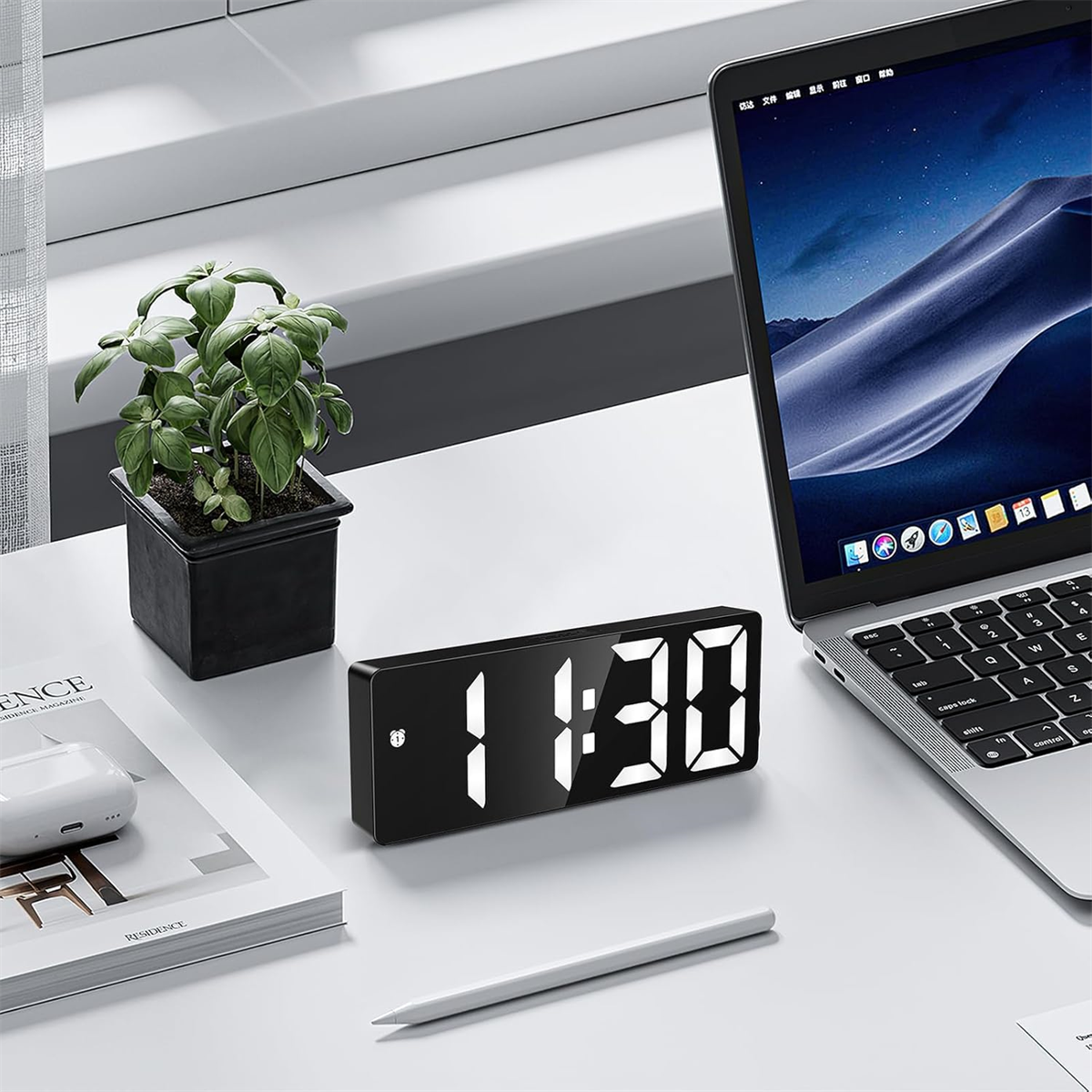 Schwarzer digitaler Wecker auf weißem Schreibtisch. Zeigt 11:30 Uhr. Es gibt einen Laptop, eine Pflanze und einen Stift.