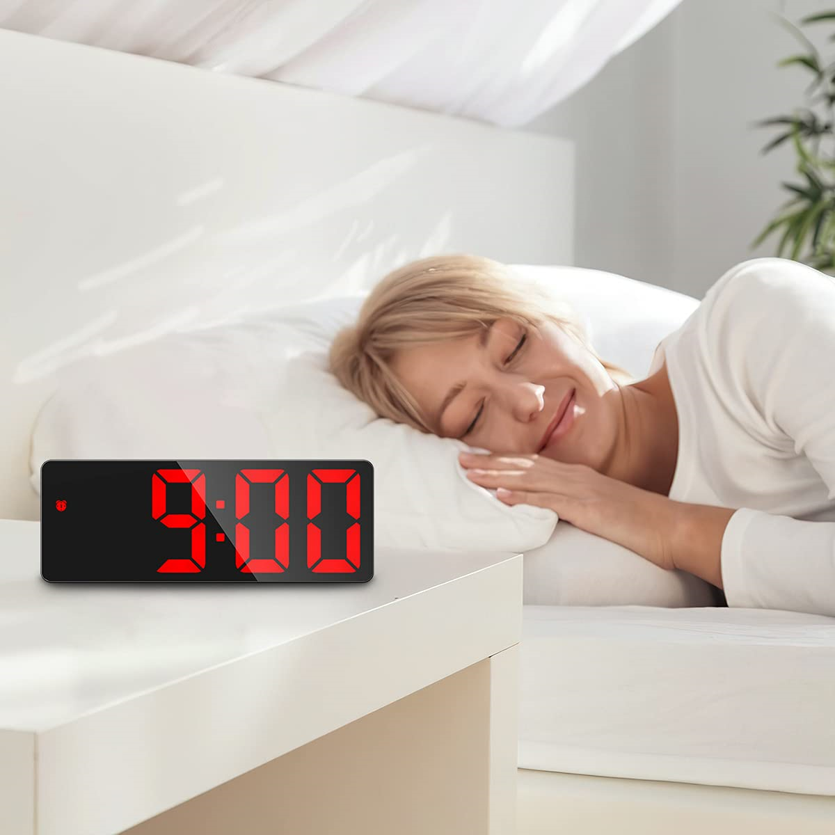 Eine schlafende Frau im Bett neben einem Tisch mit einer Digitaluhr, die 9:00 in roten Ziffern anzeigt.