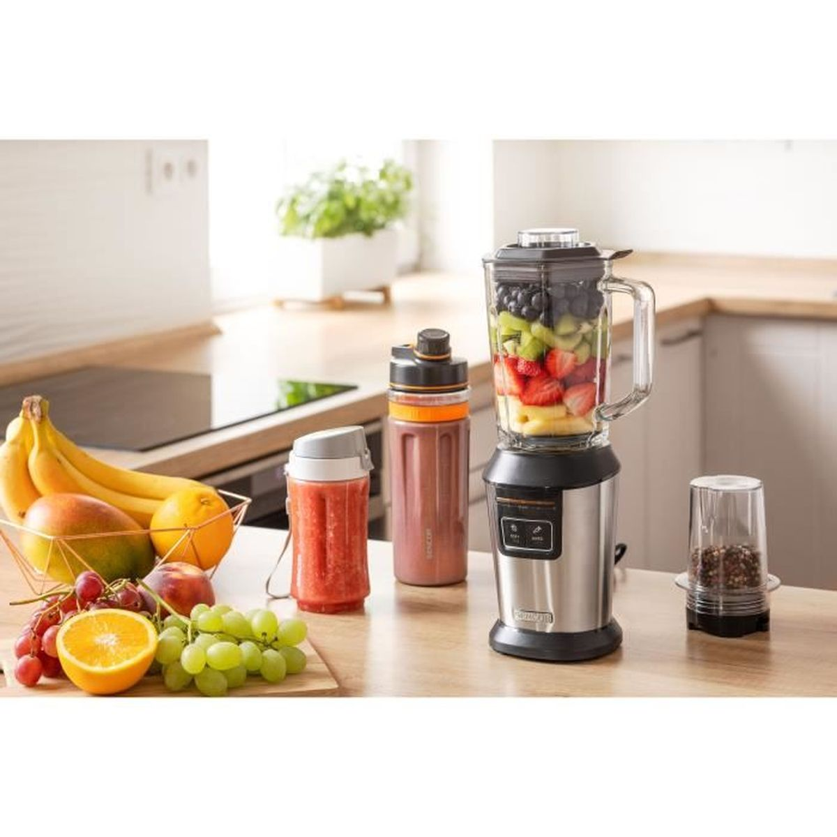 Frullatore con frutta e uno smoothie. Frutta sul tavolo. Cucina bianca.