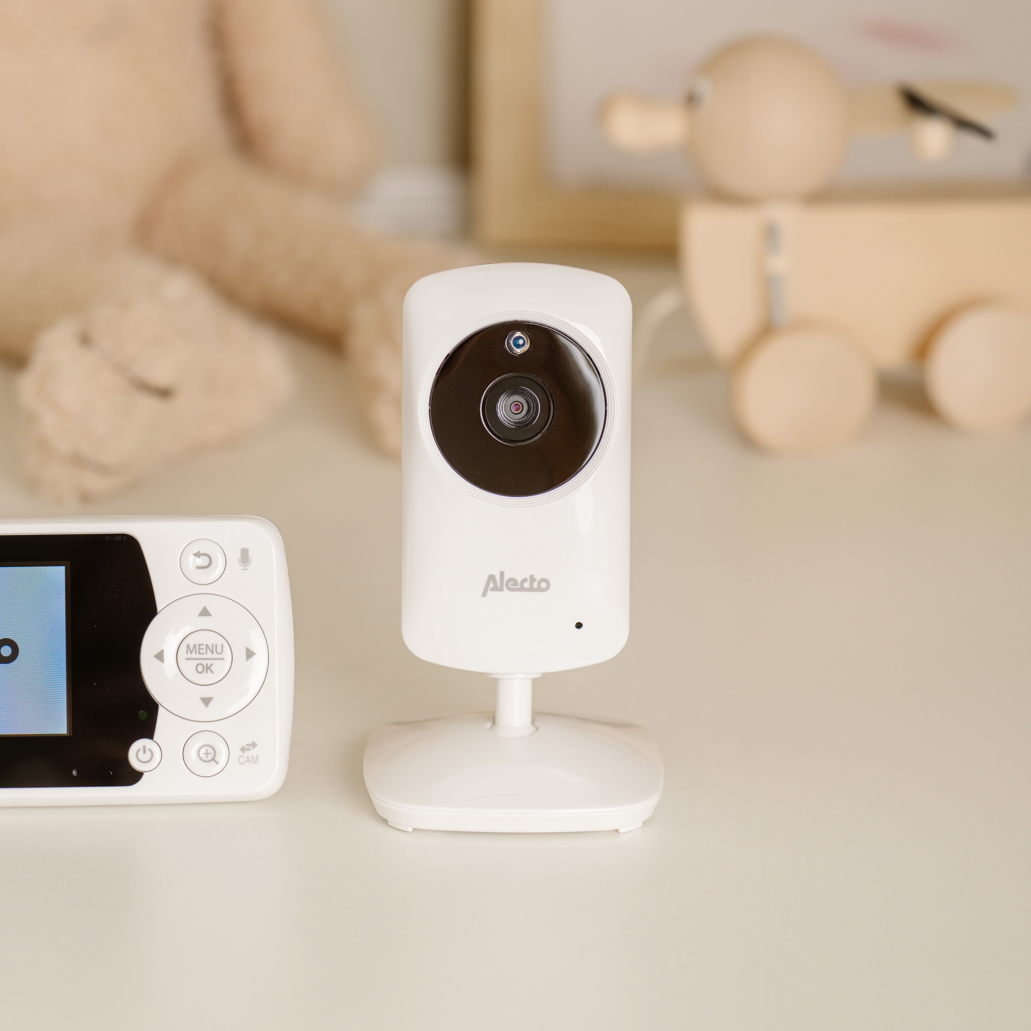 Un monitor para bebés blanco con una cámara y una pantalla sobre una superficie blanca.