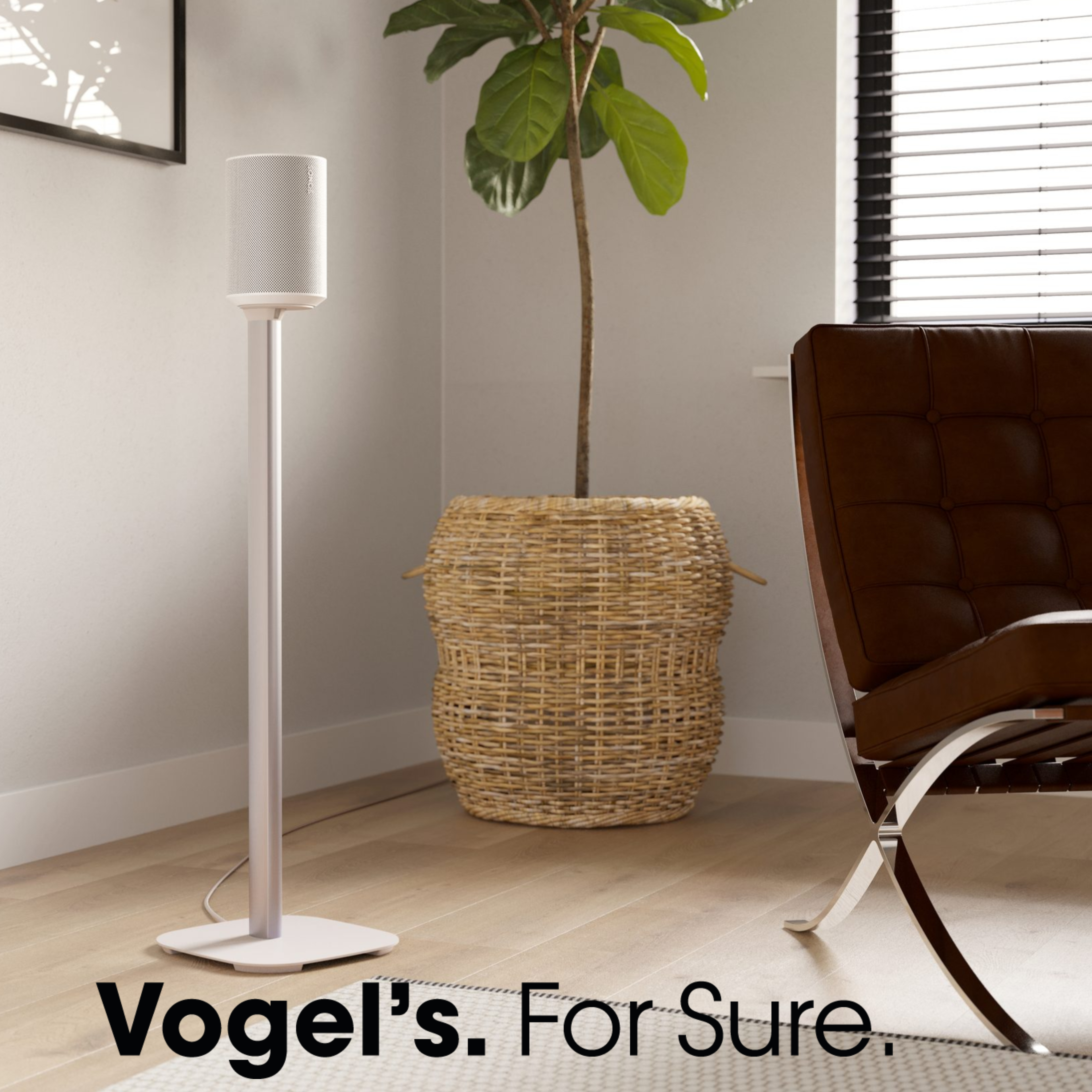 A white speaker on a stand next to a plant and a chair.