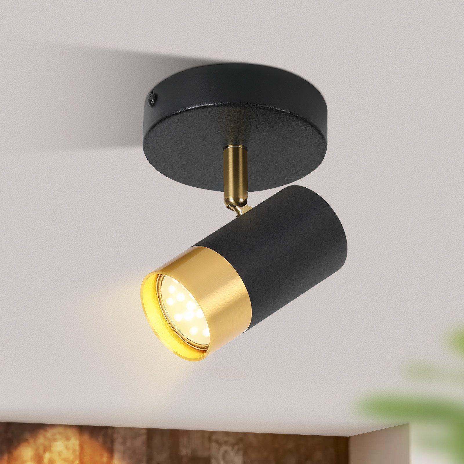 Un moderno faretto da soffitto nero e oro, montato su un soffitto bianco.