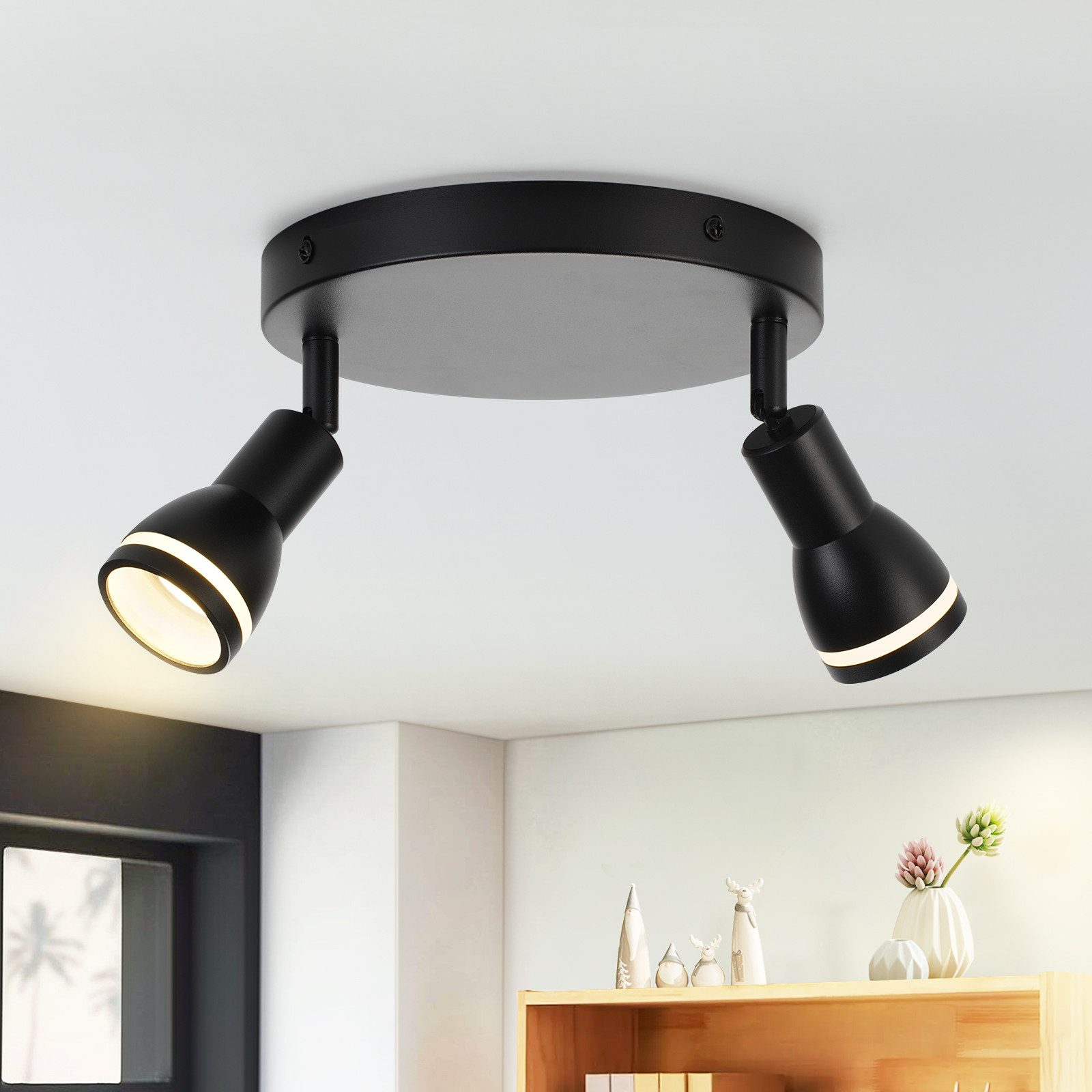 Due faretti neri montati a soffitto. Le luci sono accese.
