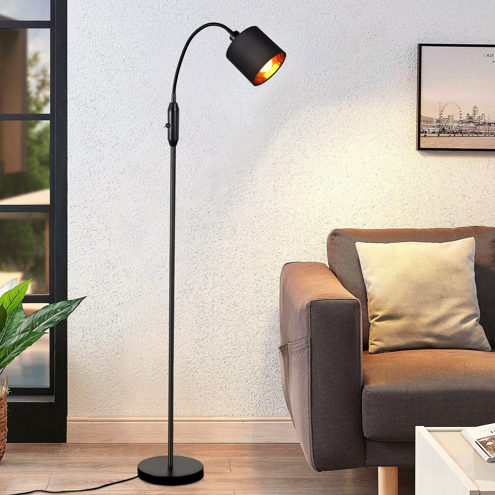 Eine schwarze Stehlampe mit gebogenem Arm, die ein Wohnzimmer beleuchtet.