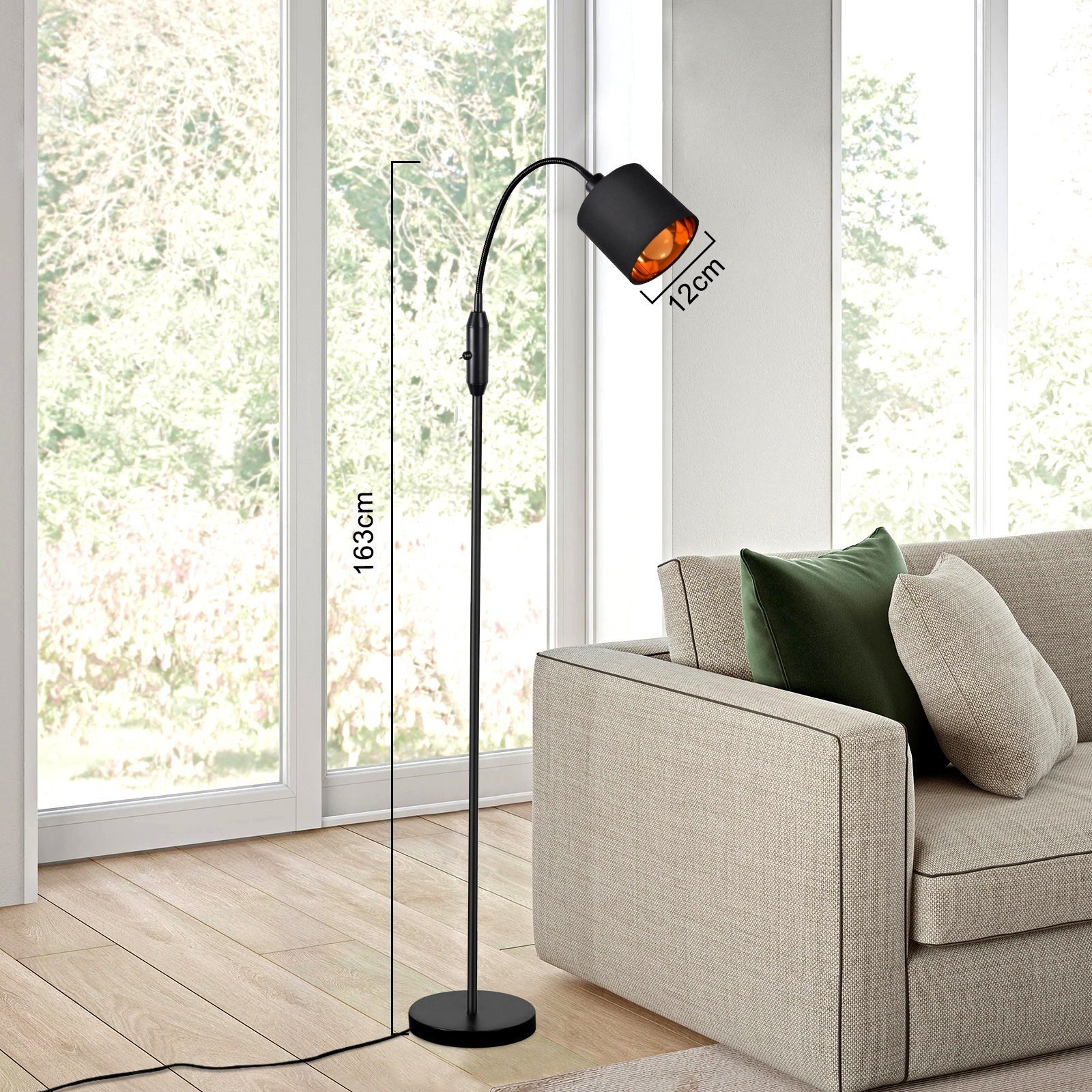 Eine hohe, schwarze Stehlampe mit gebogenem Hals. Die Lampe steht neben einem Sofa und Fenster.
