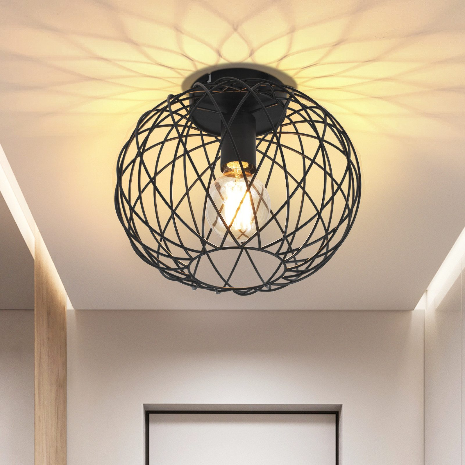 Un apparecchio per illuminazione a soffitto in metallo nero con un design a gabbia sferica, che illumina una stanza.