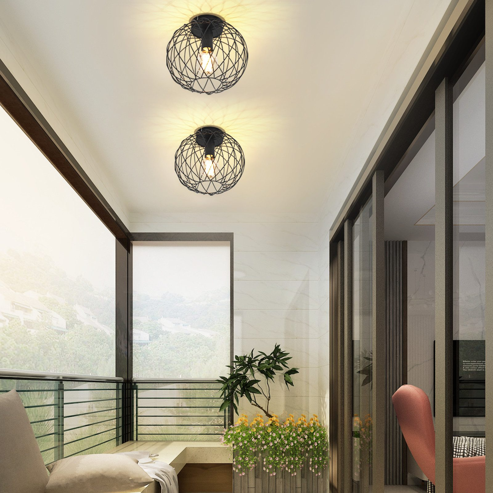 Due luci a soffitto rotonde, nere, con struttura metallica. Sono installate su un balcone con porte in vetro e vista sulla natura.