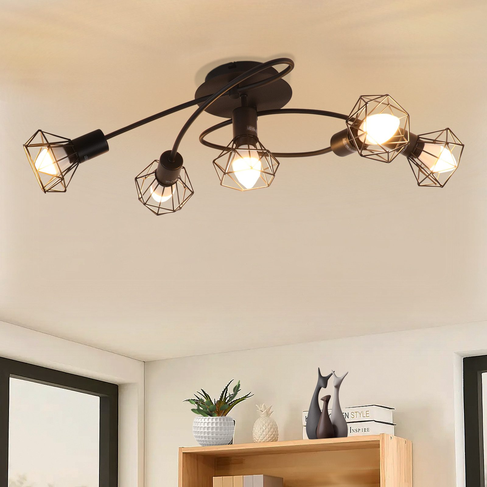 Czarna lampa sufitowa z pięcioma oprawami o geometrycznych kształtach. Biały sufit.